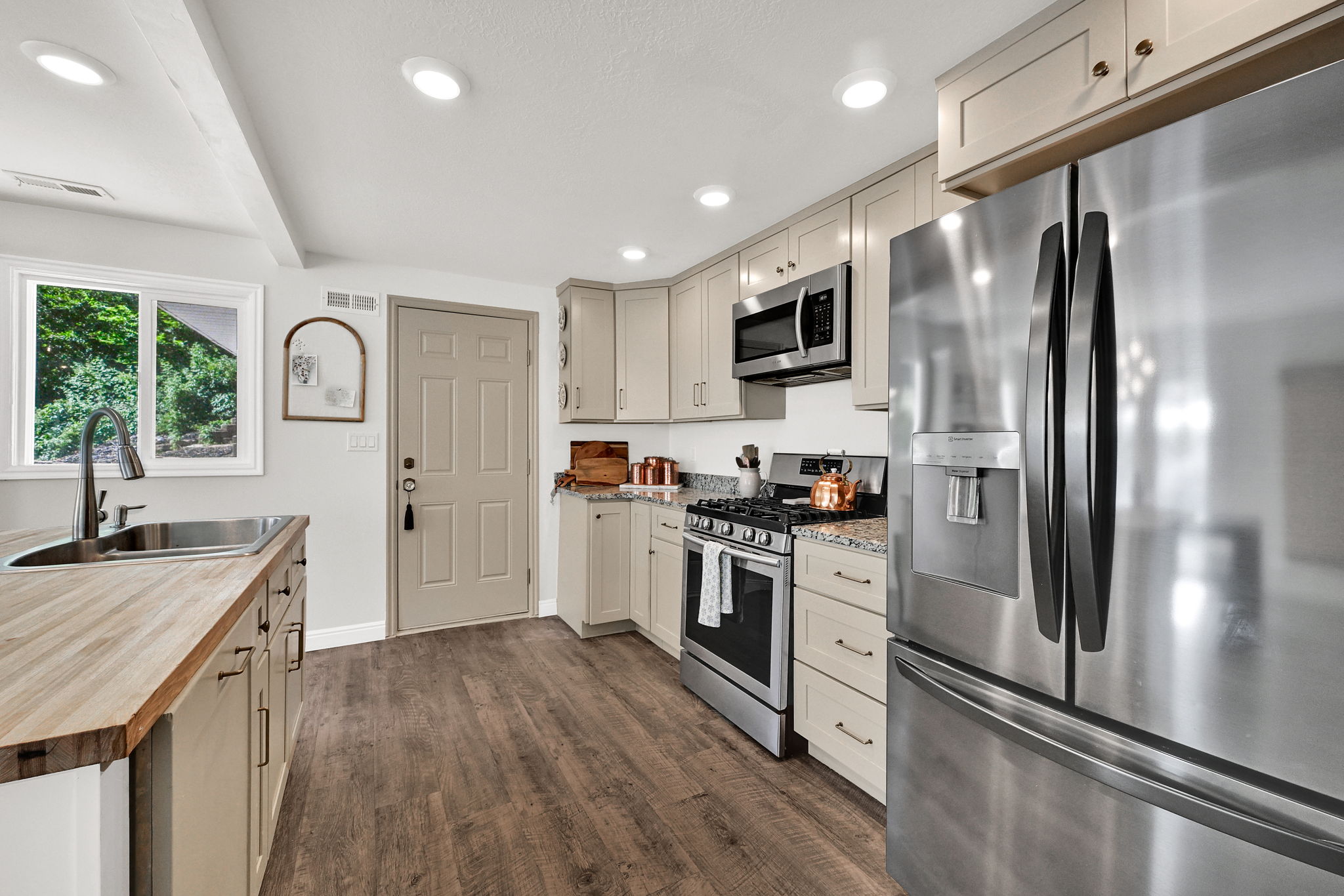 Modern kitchen featuring stainless steel appliances, light-toned cabinetry, wood-finish flooring, recessed lighting, and butcher block countertops
