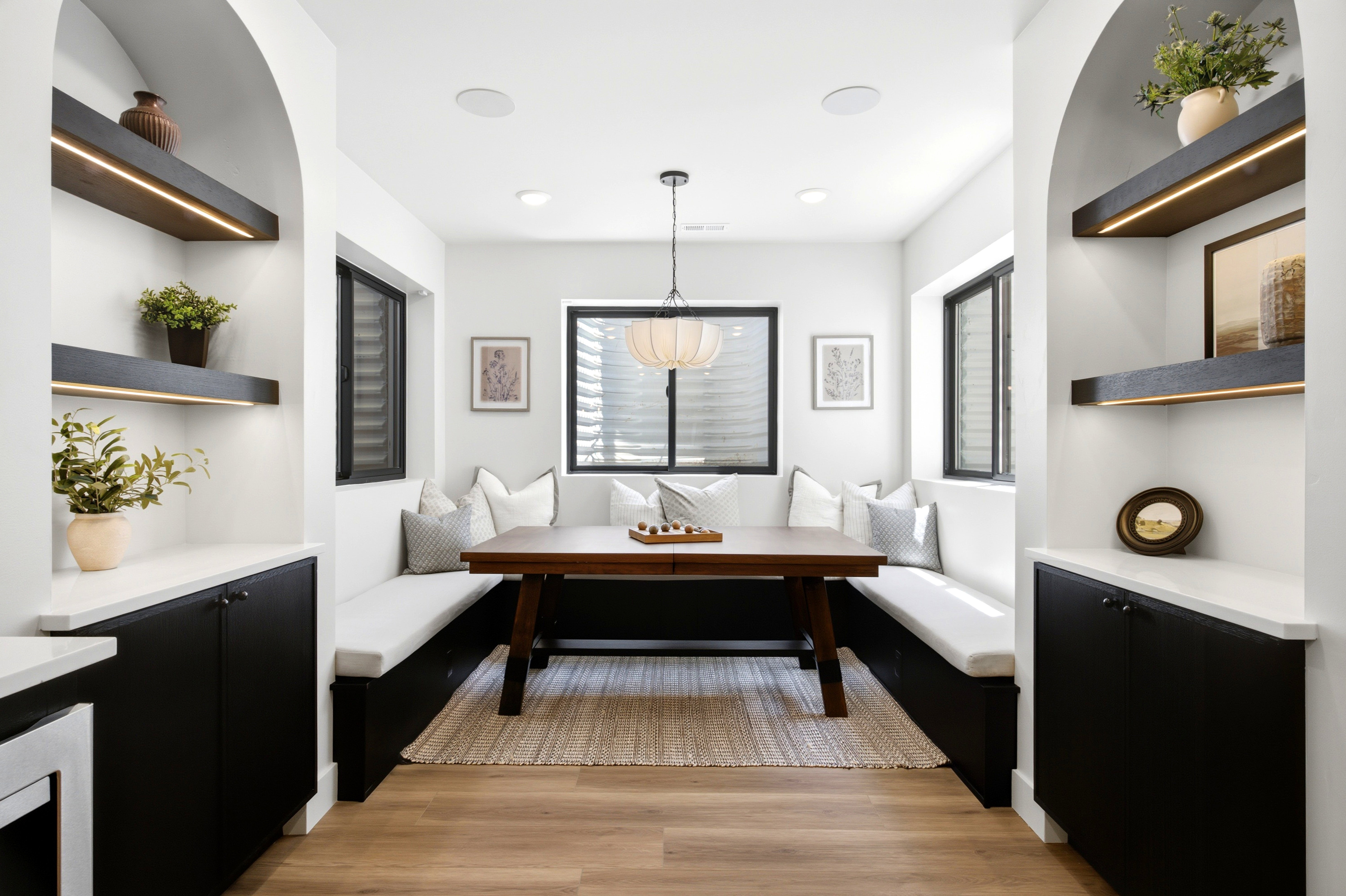 Dining area featuring built-in bench seating with cushions, a central dark wood table, and light wood-finish flooring