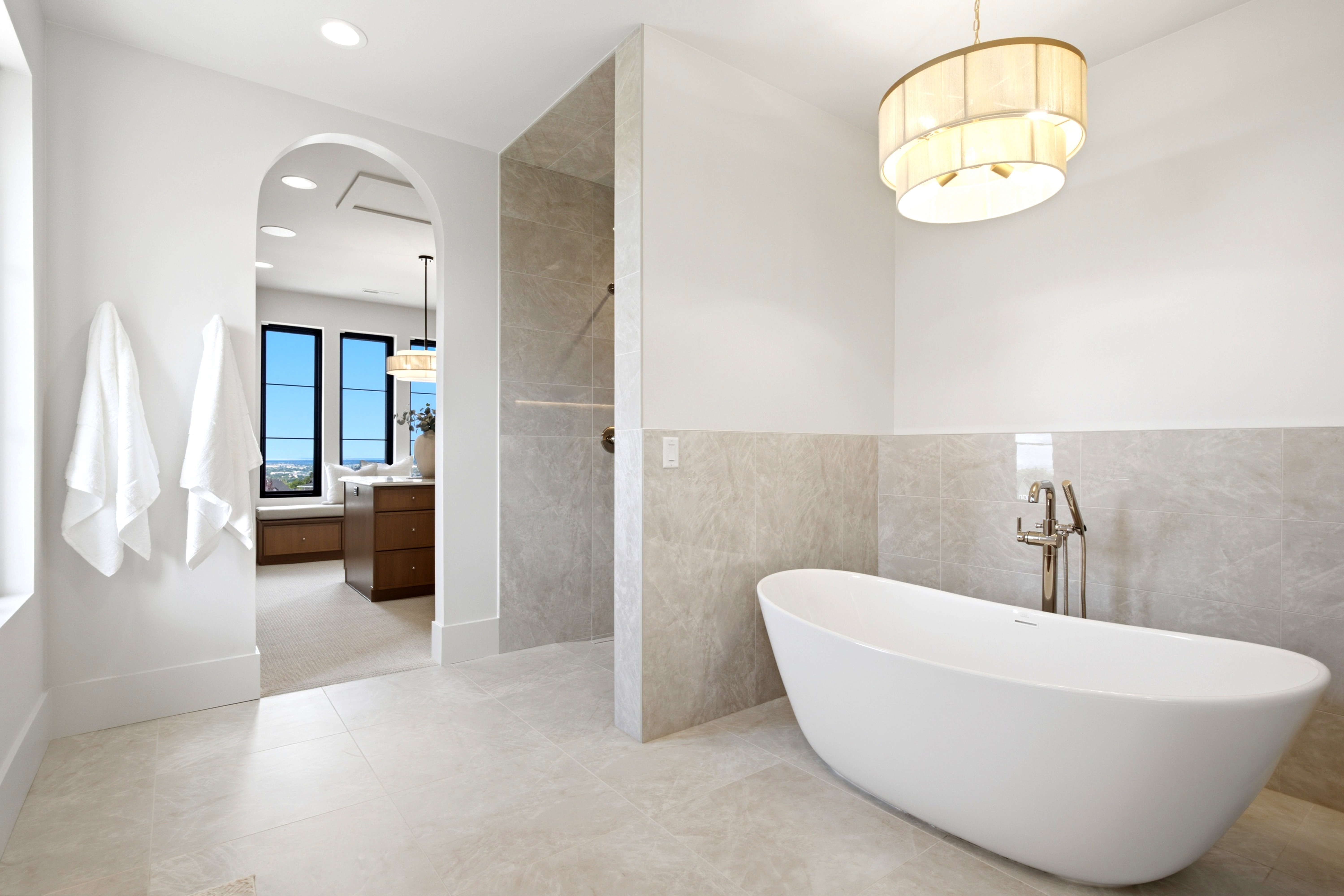 Contemporary bathroom featuring a freestanding soaking tub with floor-mounted faucet, tile flooring, and a tiled shower enclosure