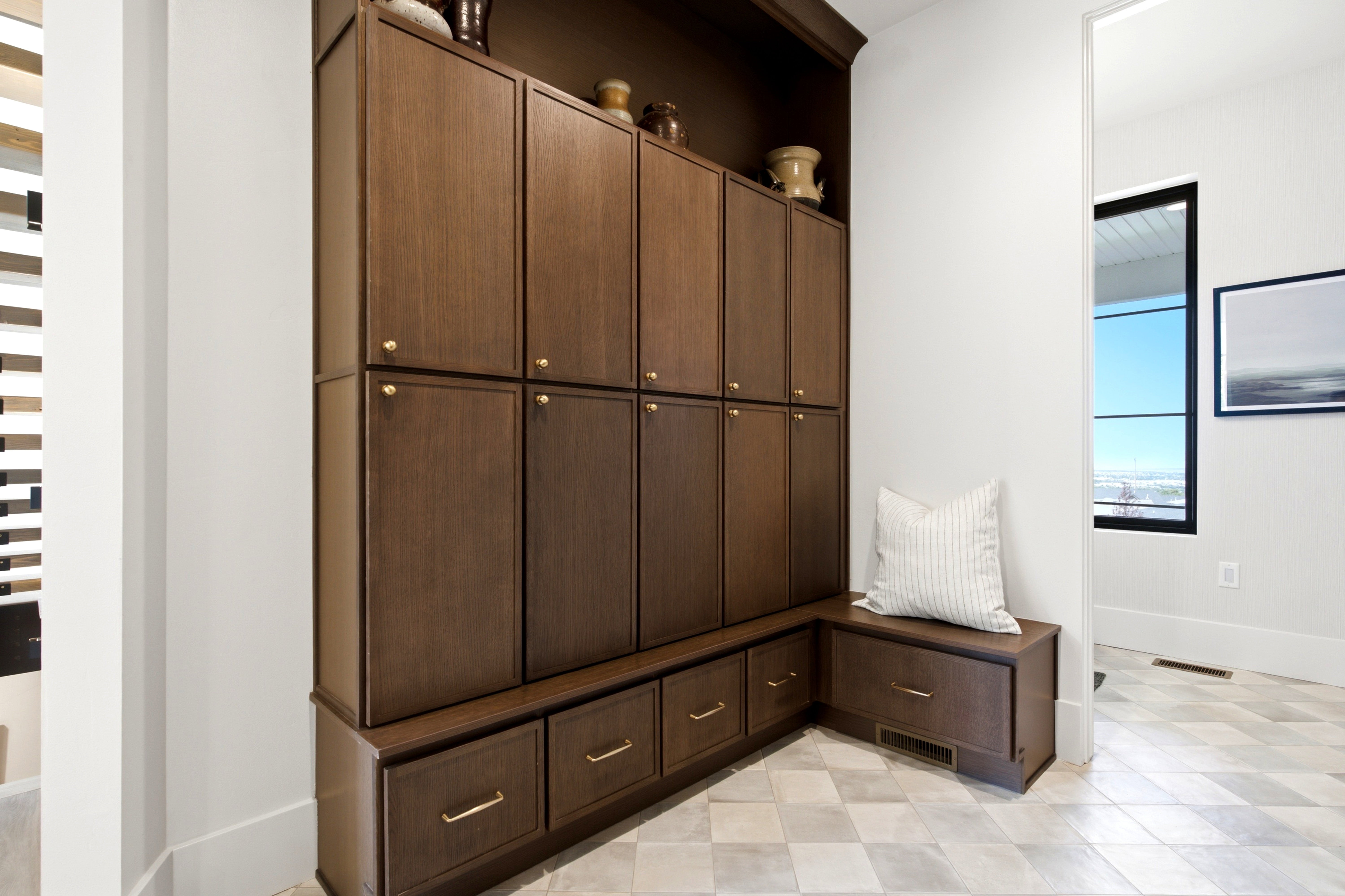 Built-in wood cabinetry with brass hardware, integrated bench seating, and patterned tile flooring