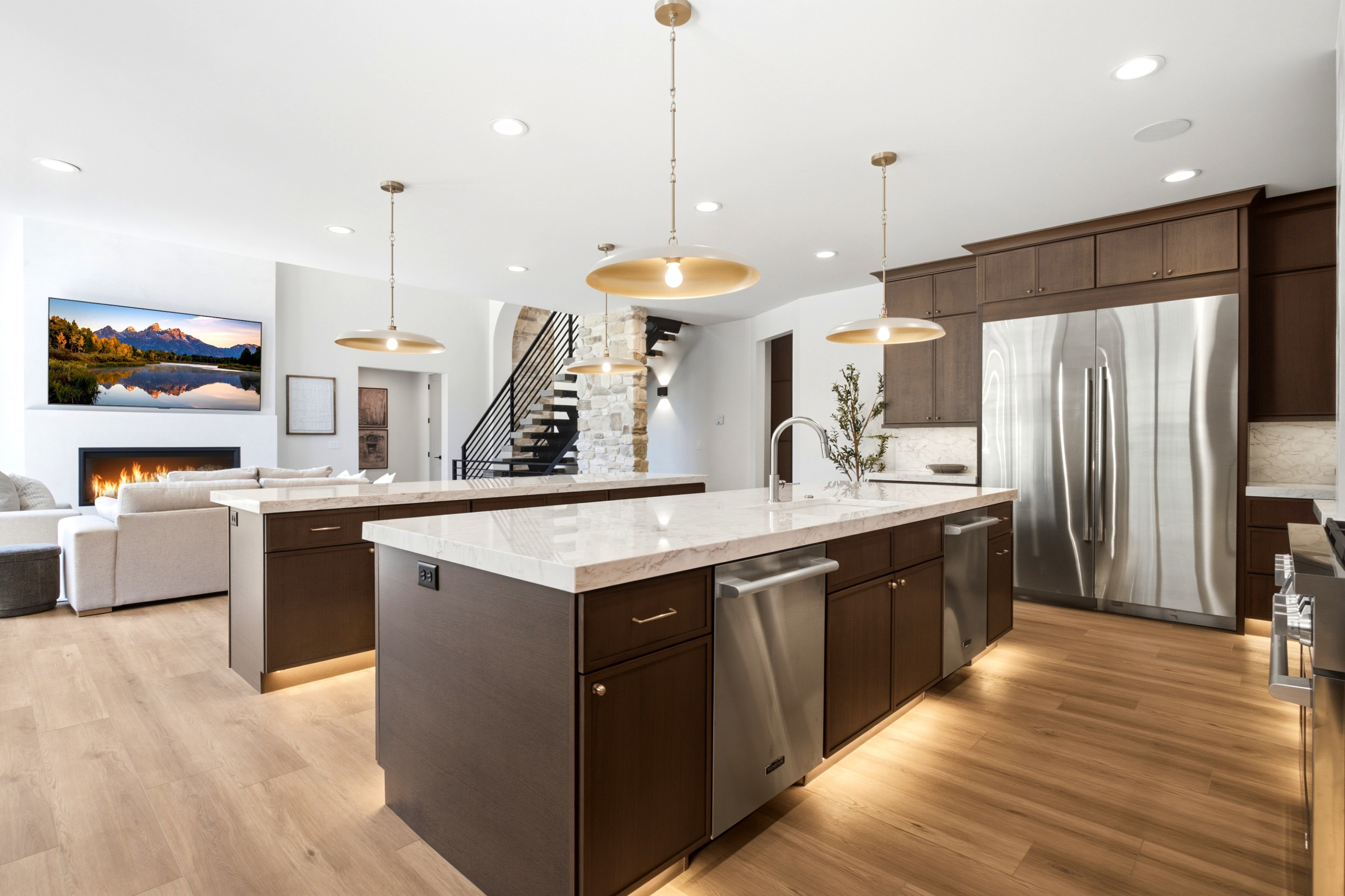 Gourmet kitchen featuring two islands with stone countertops, integrated stainless steel appliances, dark wood cabinetry, and wood-finish flooring