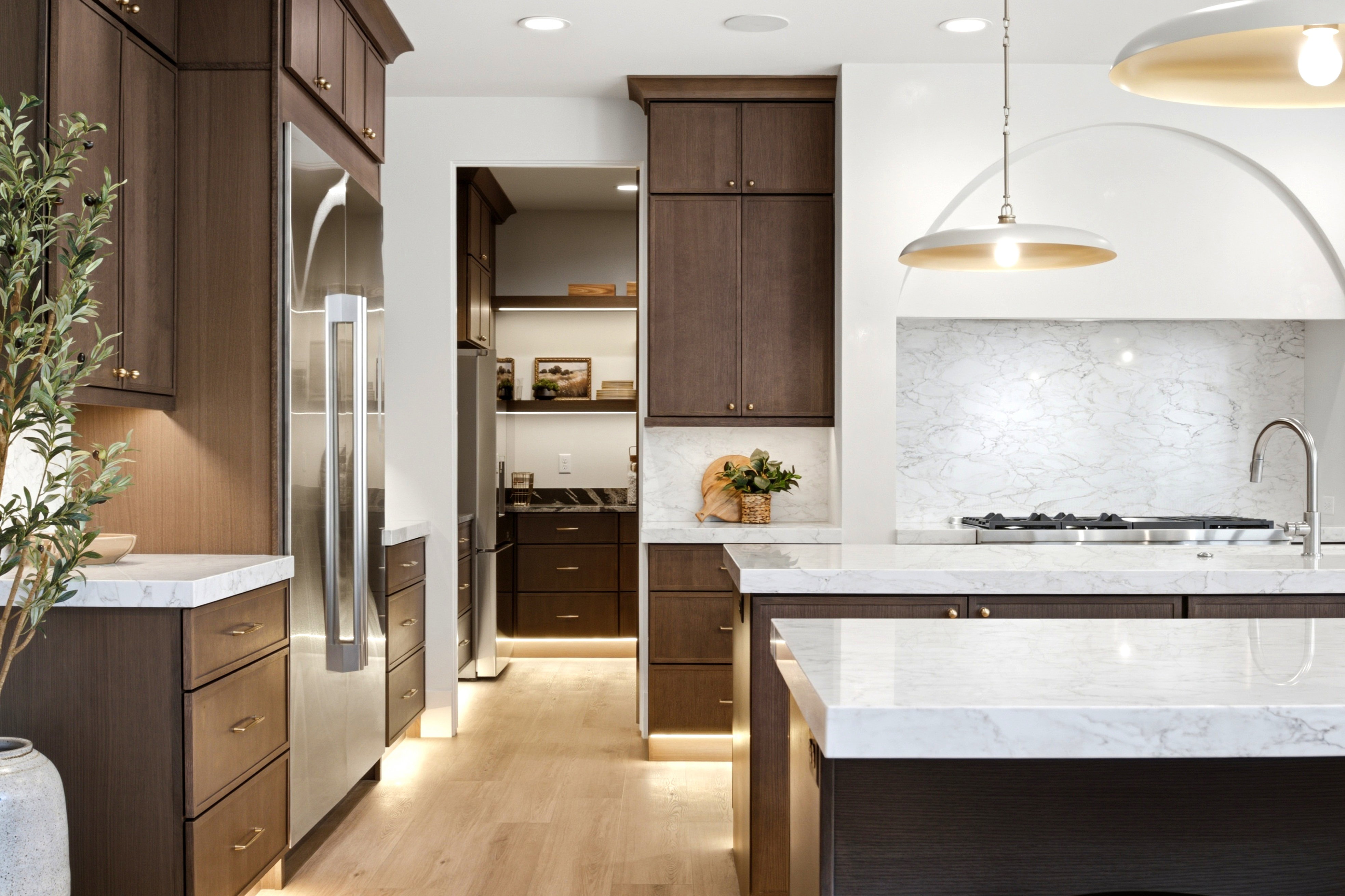Contemporary kitchen featuring dark wood-finish cabinetry, light wood-finish flooring, and white countertops
