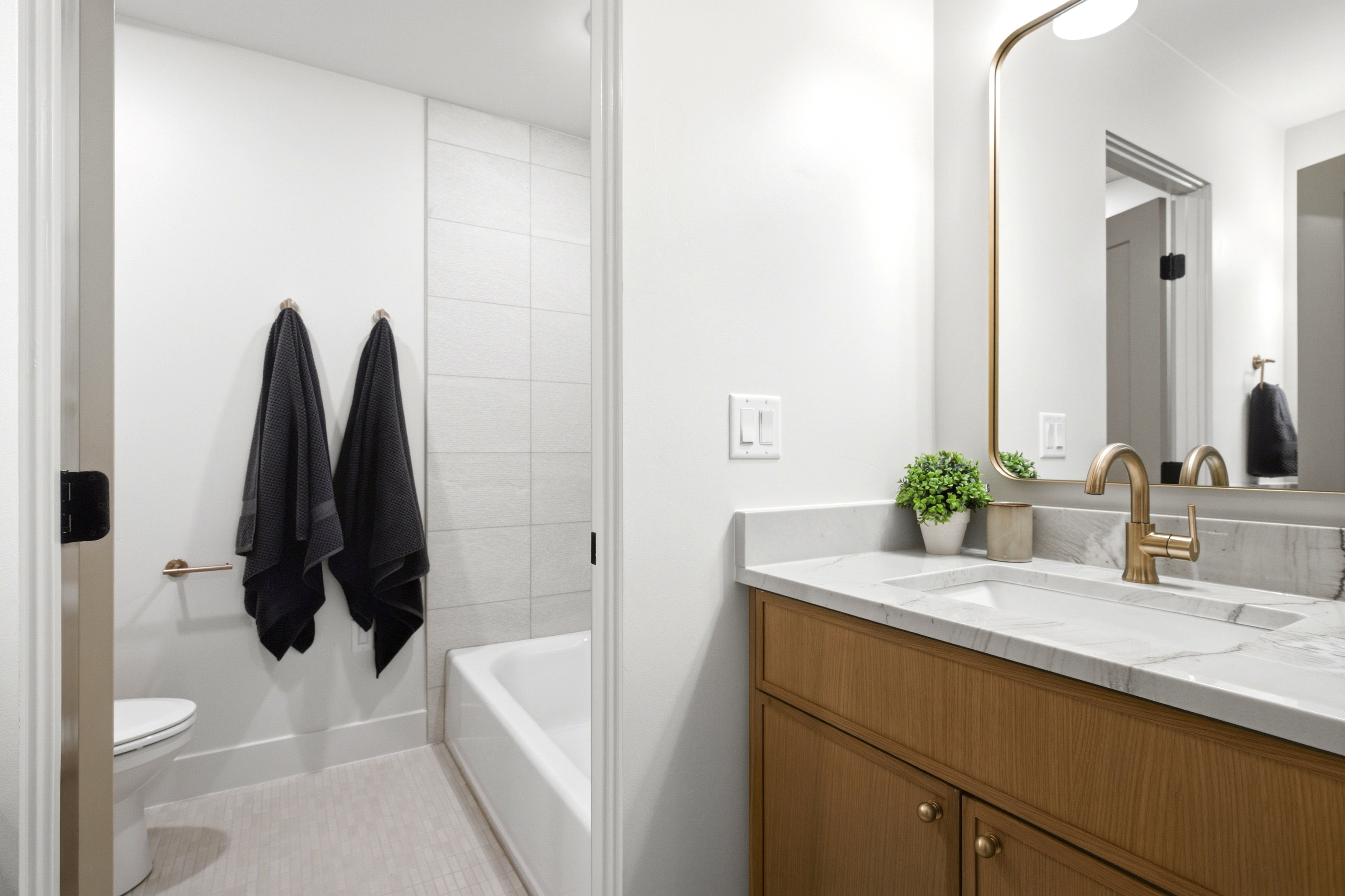 Bathroom featuring a wood-finish vanity with a light-toned countertop, an undermount sink, and a gold-finish faucet