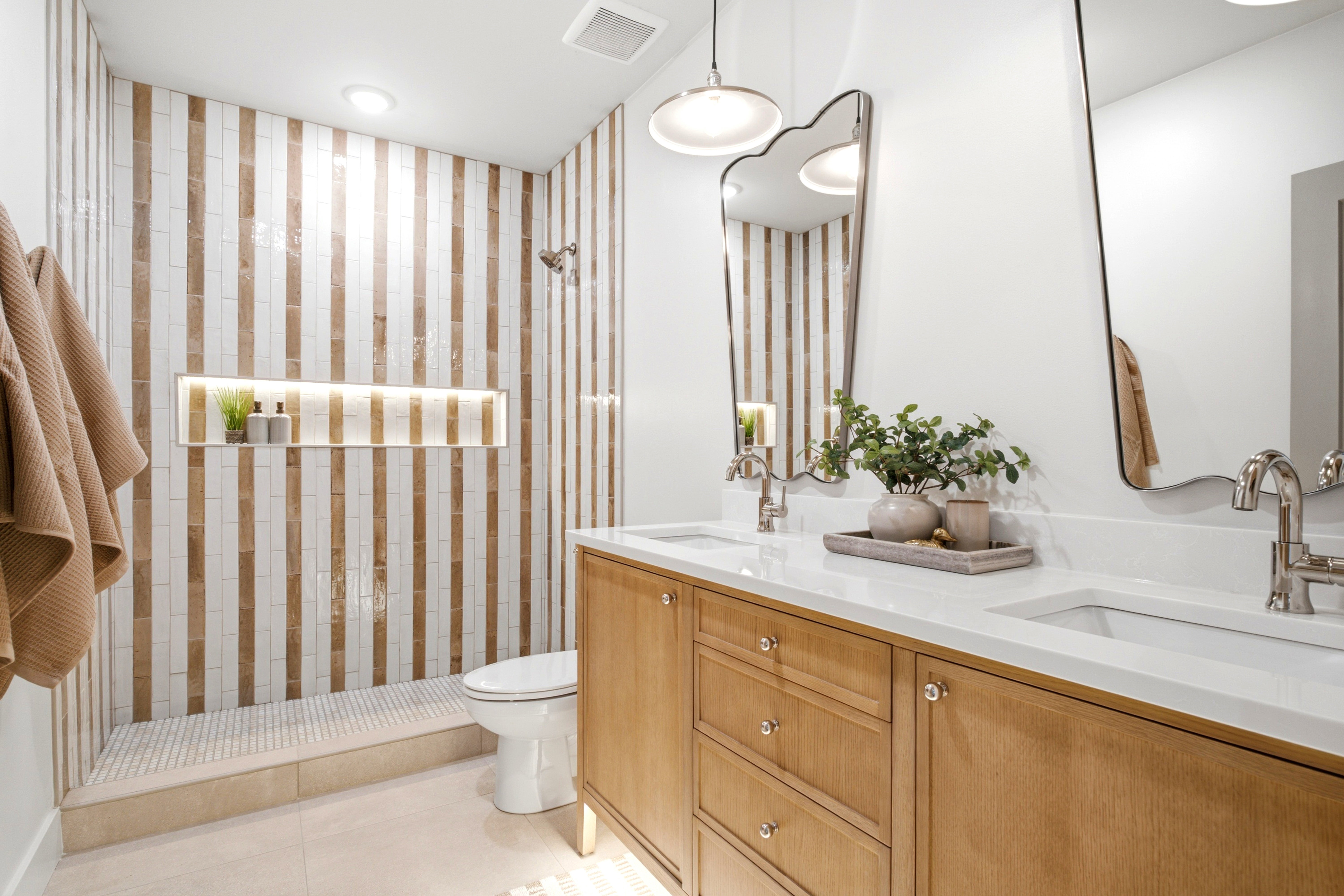 Bathroom featuring a dual vanity with light wood cabinetry, white countertops, and contemporary vessel sinks