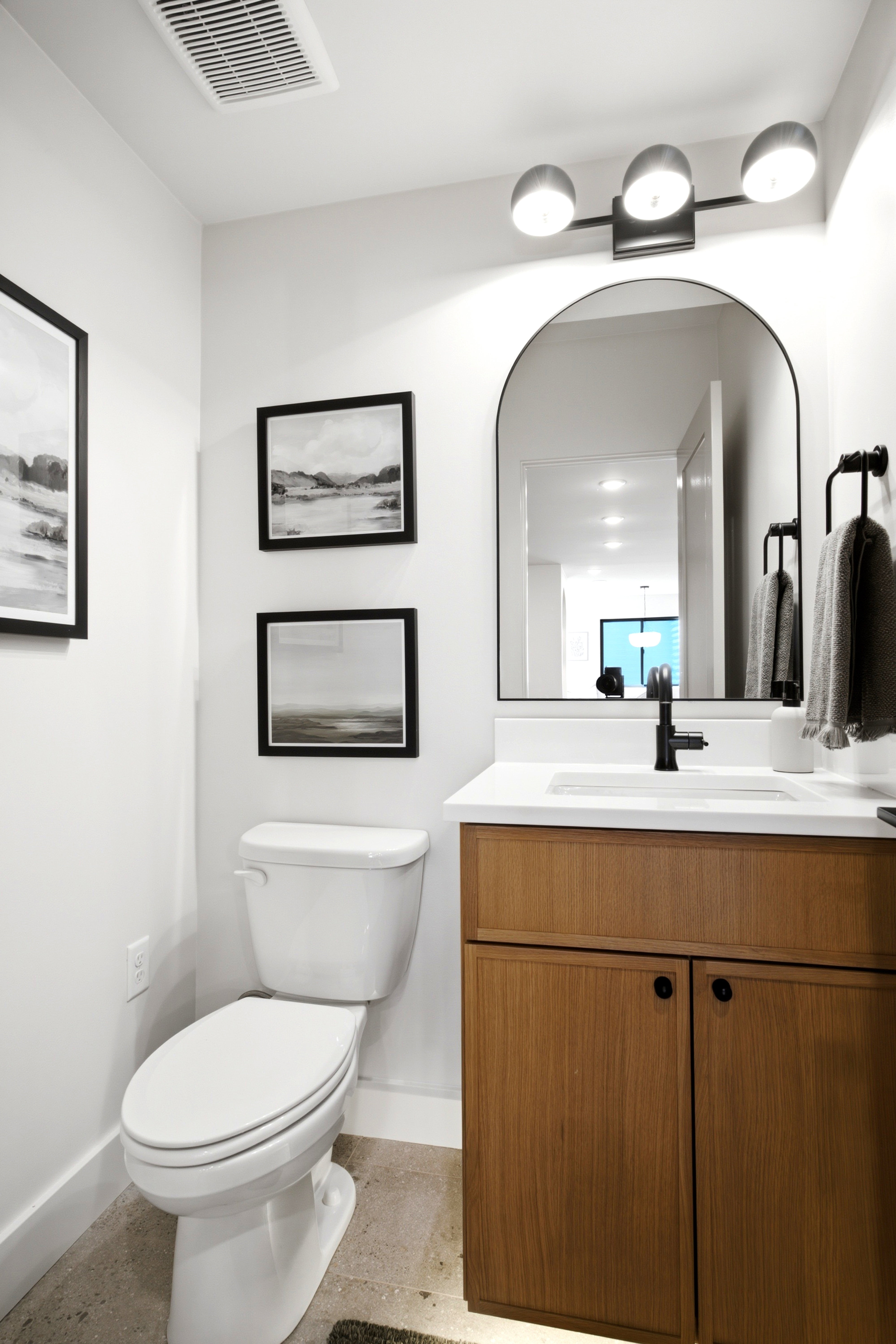 Powder room featuring a wood-finish vanity with white countertop, integrated sink, and matte black faucet