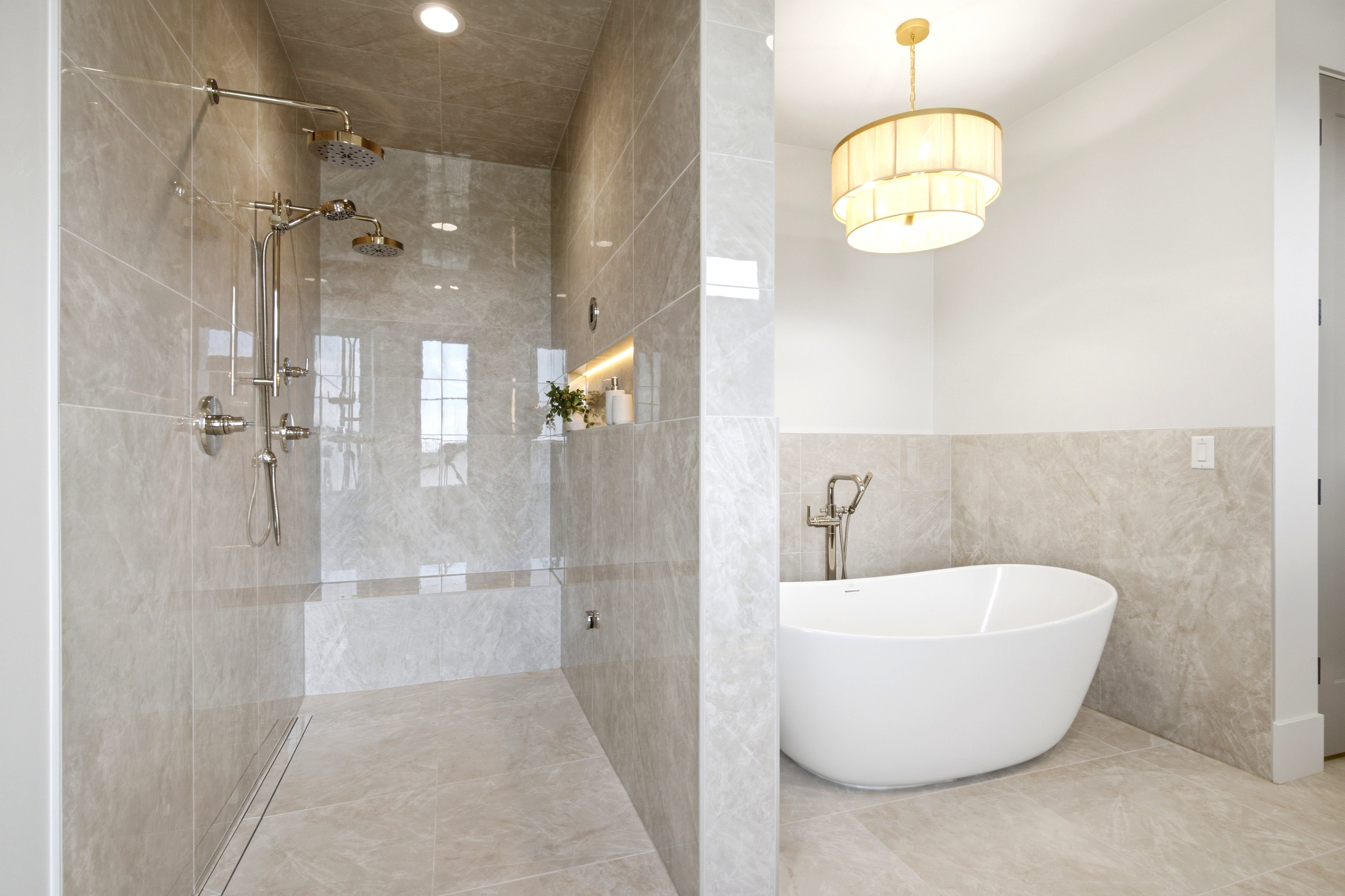 Freestanding soaking tub alongside a tiled walk-in shower with dual showerheads