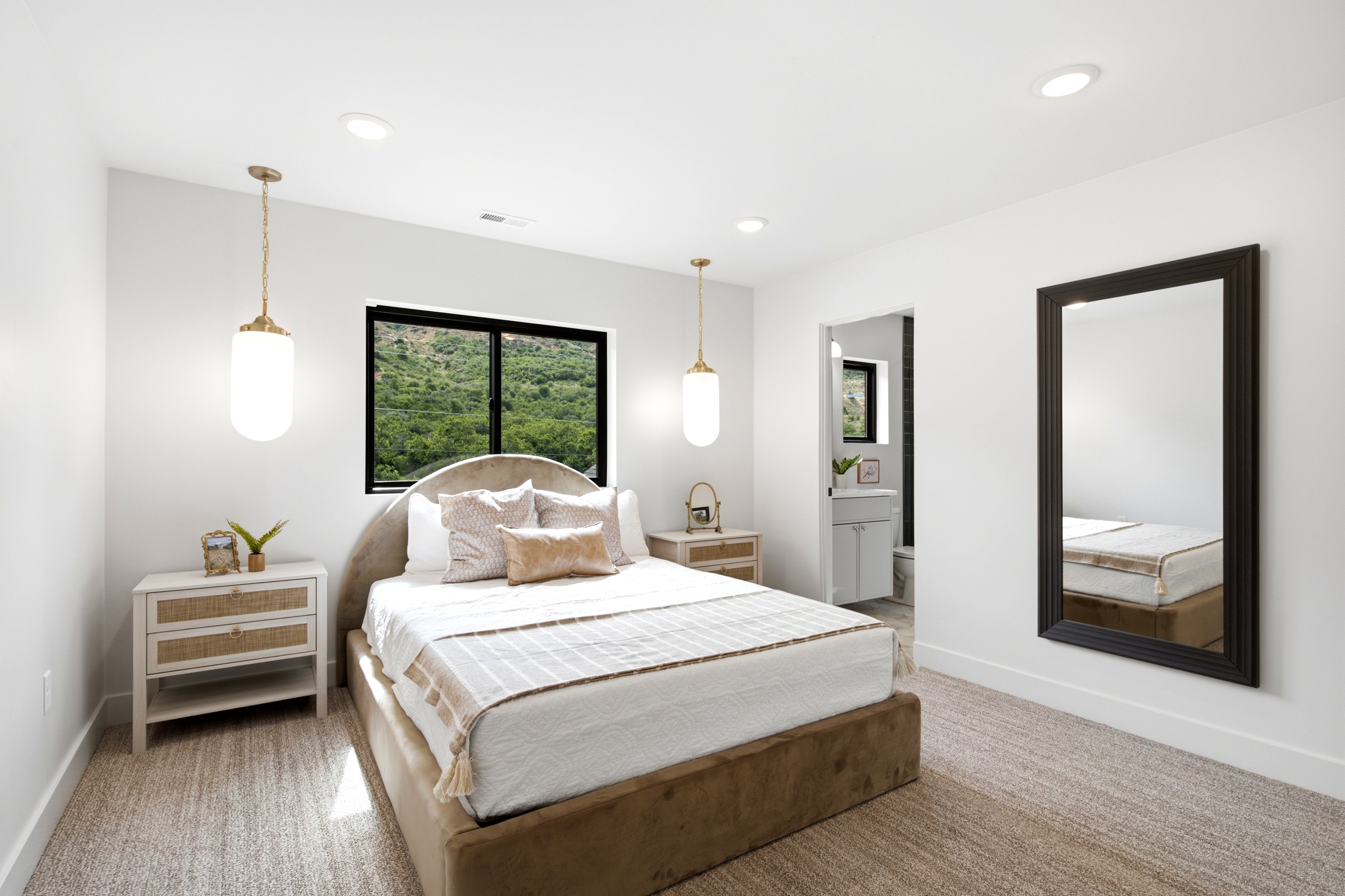 Spacious bedroom featuring recessed lighting, two pendant light fixtures, and a large window with black trim