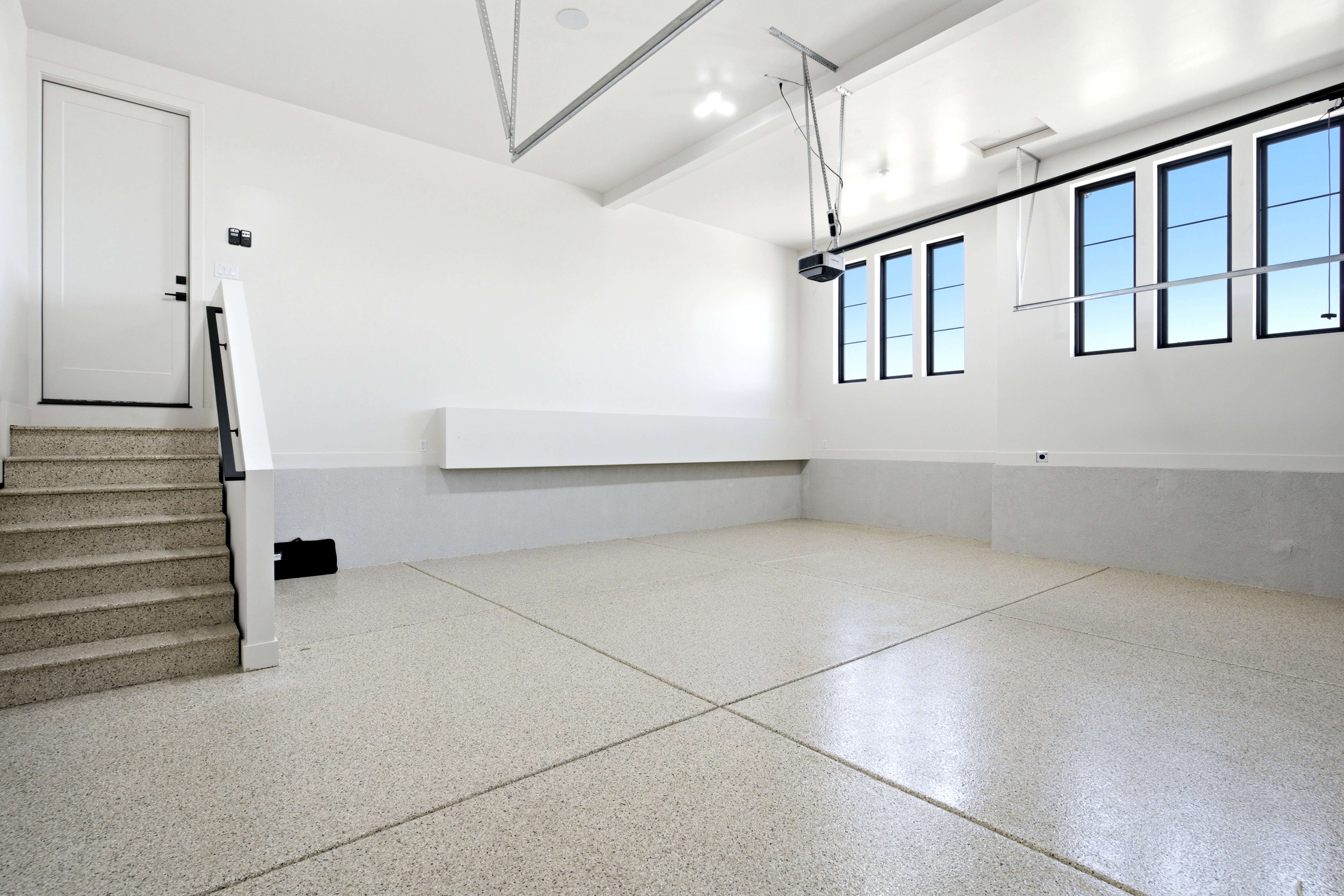 Spacious garage featuring a durable epoxy floor, multiple windows, a private entry door, and integrated storage shelving