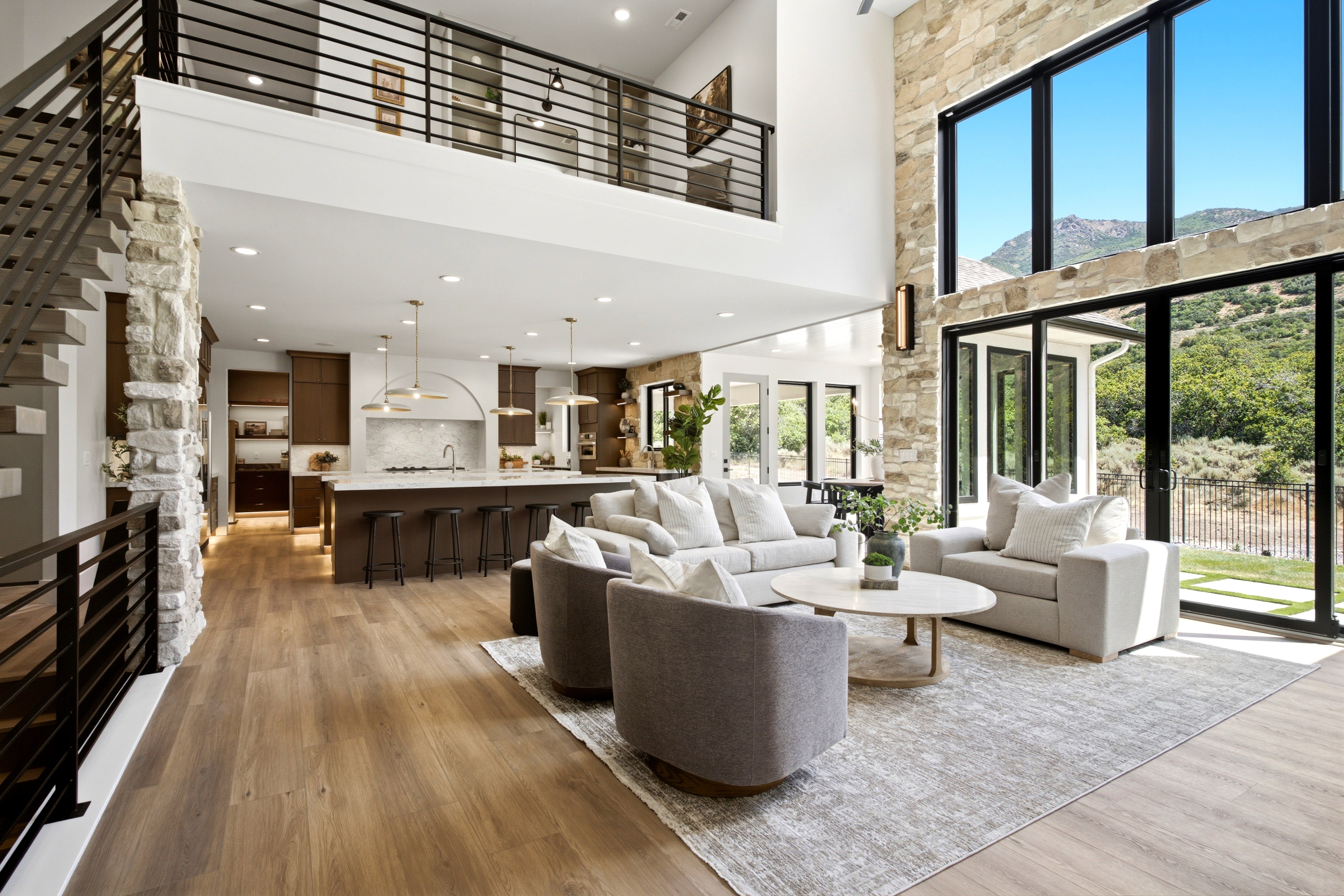 Expansive open-concept living area featuring a two-story stone accent wall, soaring ceilings, and large format windows
