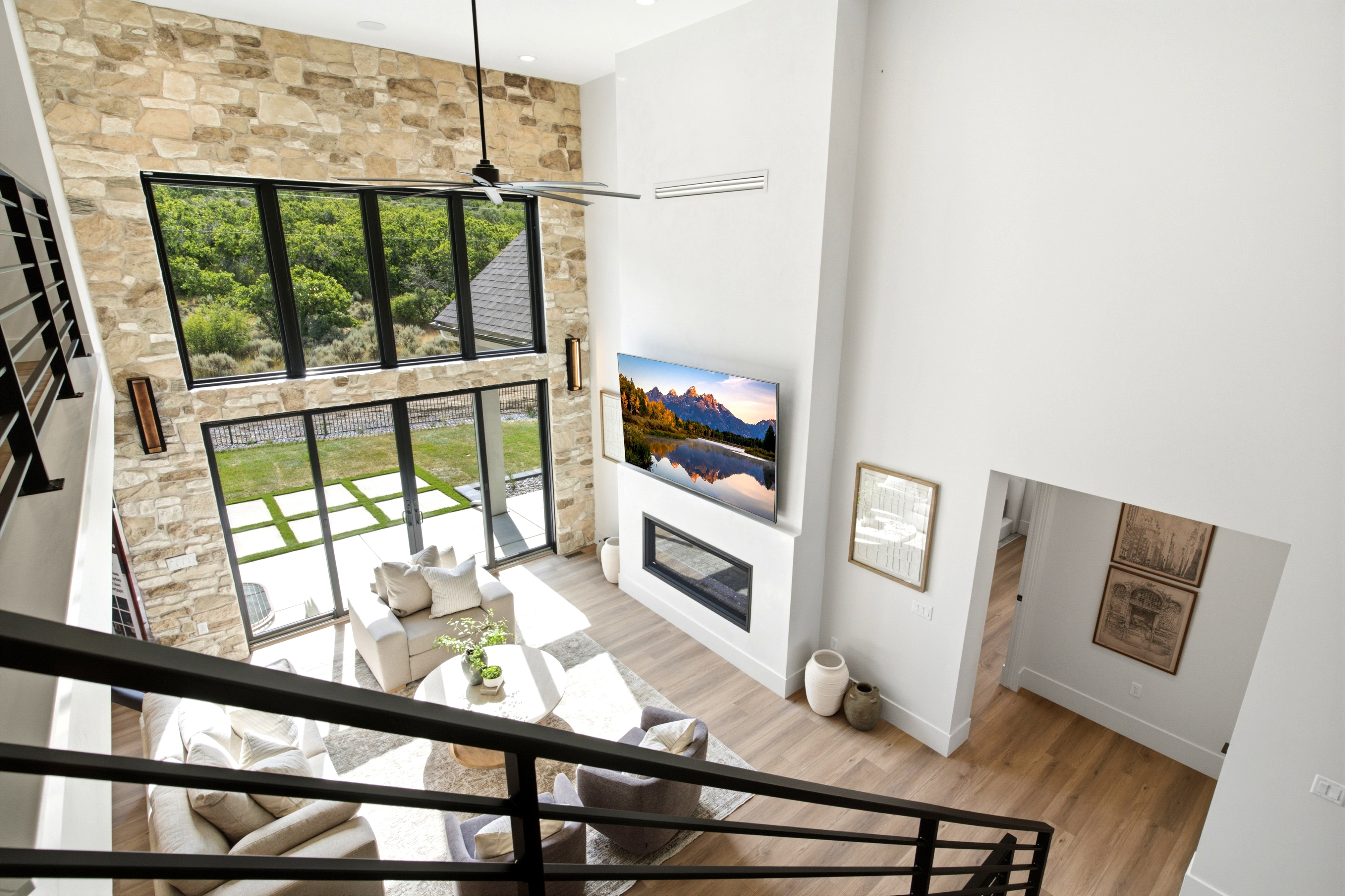 Two-story living area featuring a stone accent wall, soaring ceilings, and expansive floor-to-ceiling windows