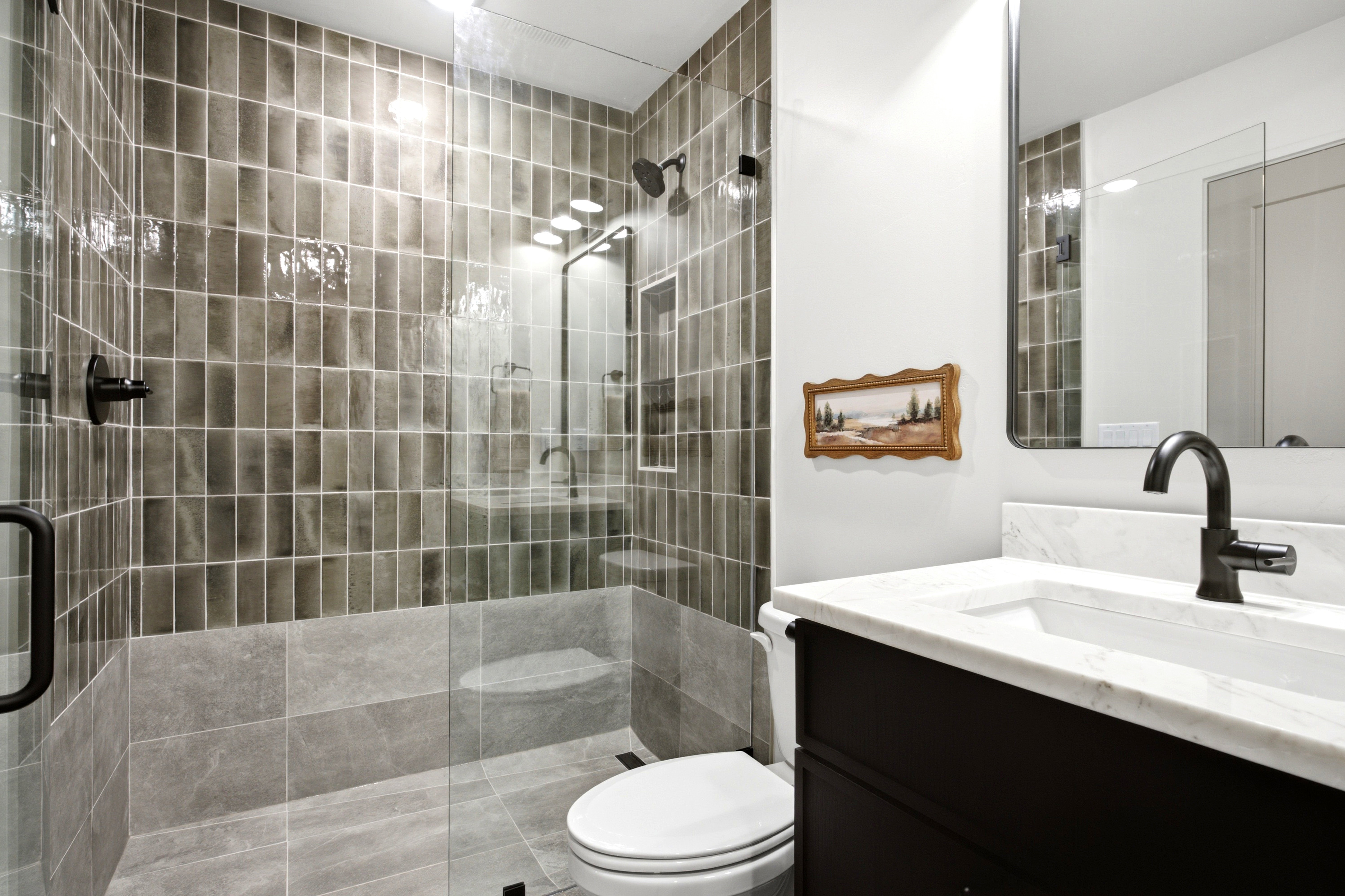 Bathroom featuring a glass-enclosed shower with vertical rectangular tiles, a built-in shower niche, and a matte black shower head