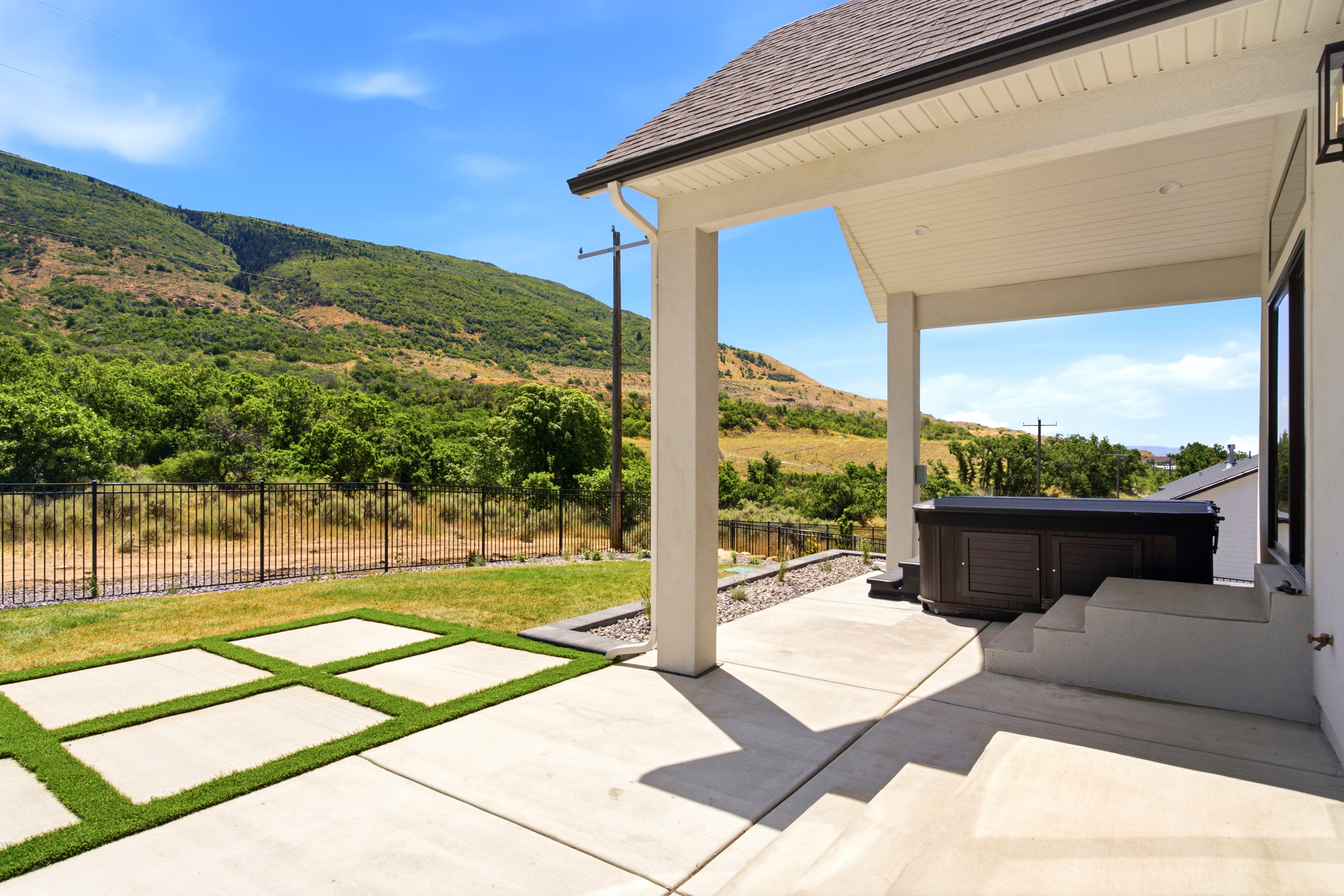 Covered patio with concrete flooring, accented by artificial turf pavers