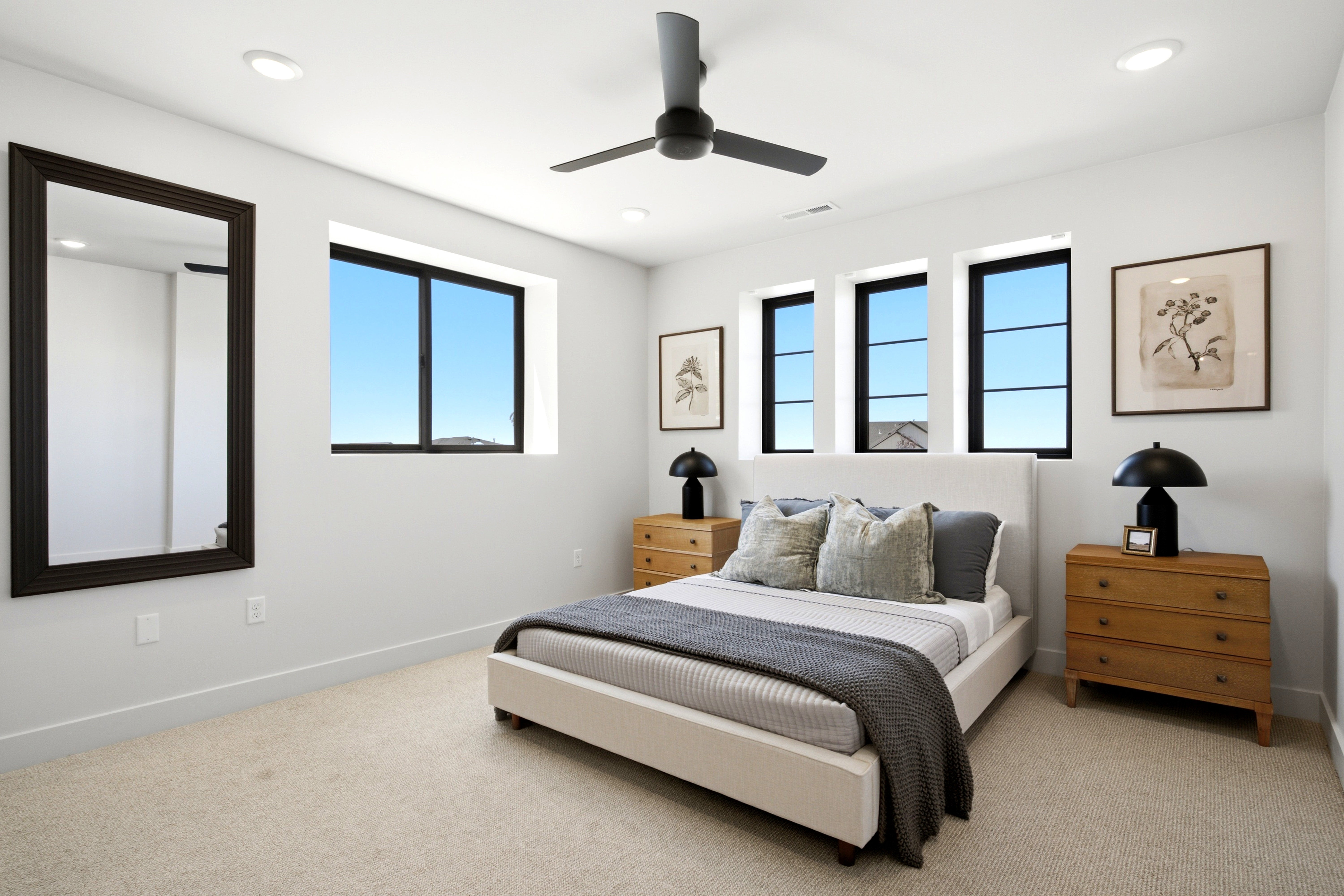 Recessed lighting illuminates this bright room featuring wall-to-wall carpeting, a ceiling fan, and multiple black-framed windows