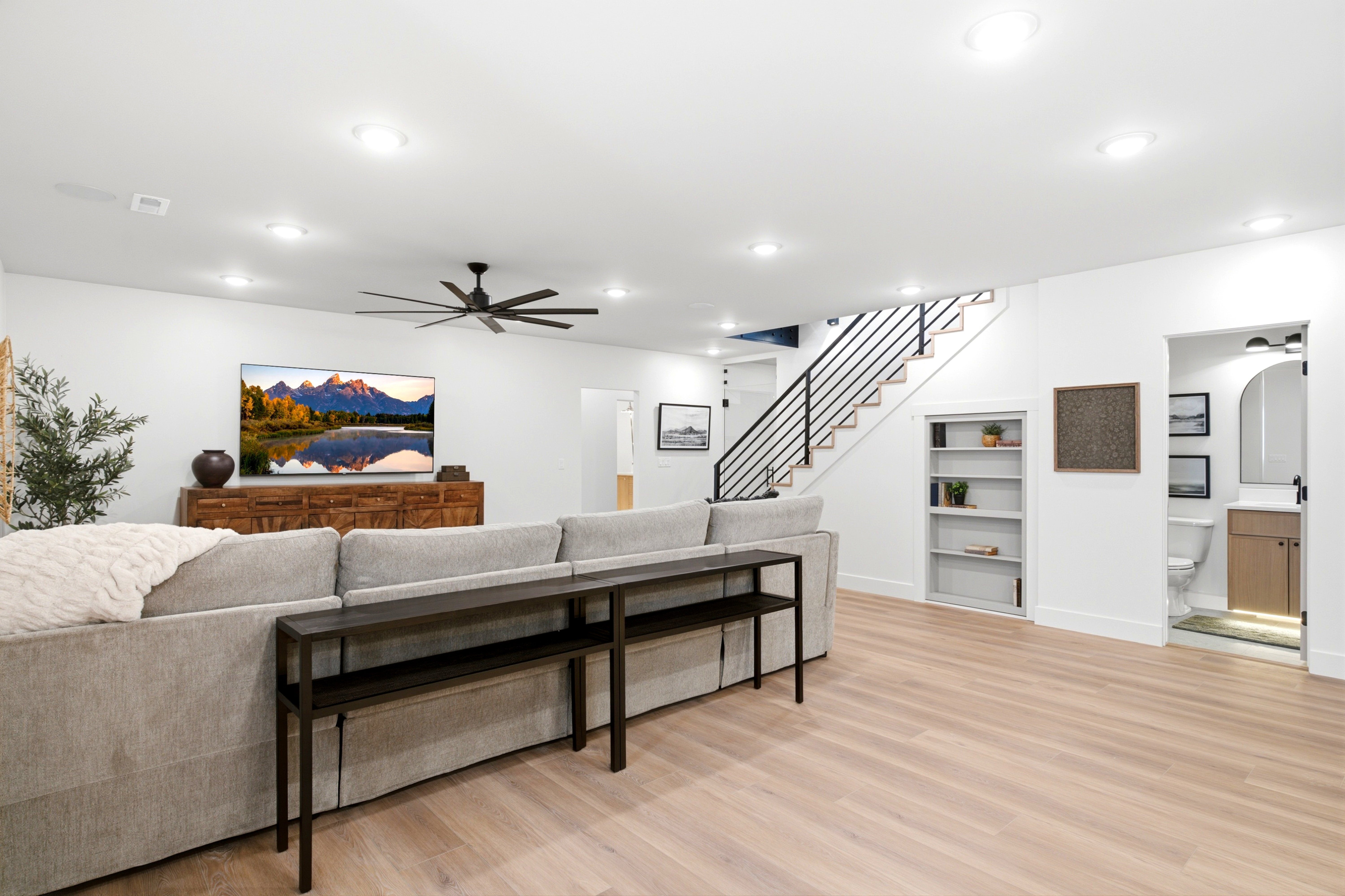 Spacious living area featuring light wood-finish flooring, recessed lighting, and a modern ceiling fan