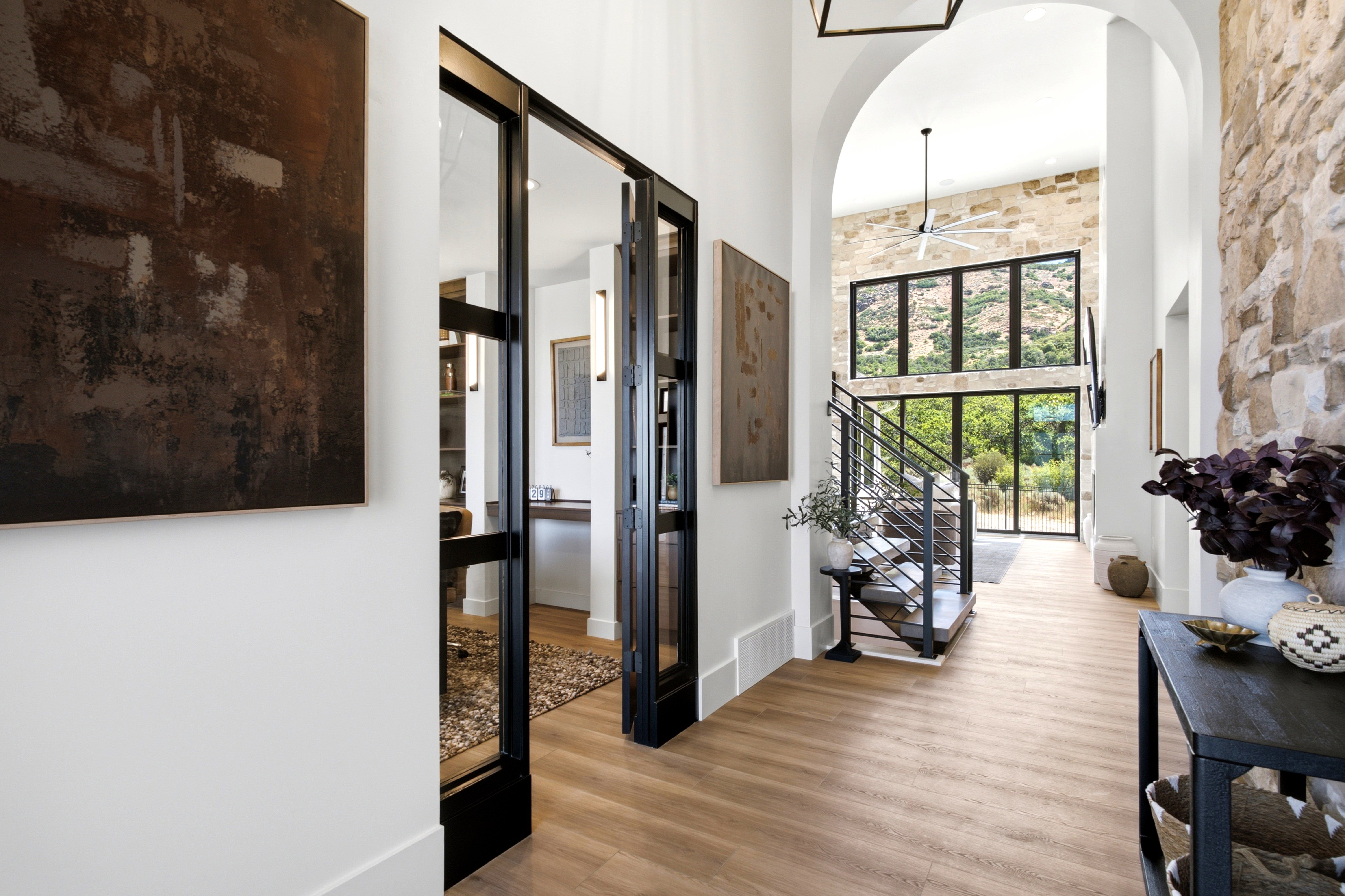 Vaulted entry with stone accent wall and wood-finish flooring