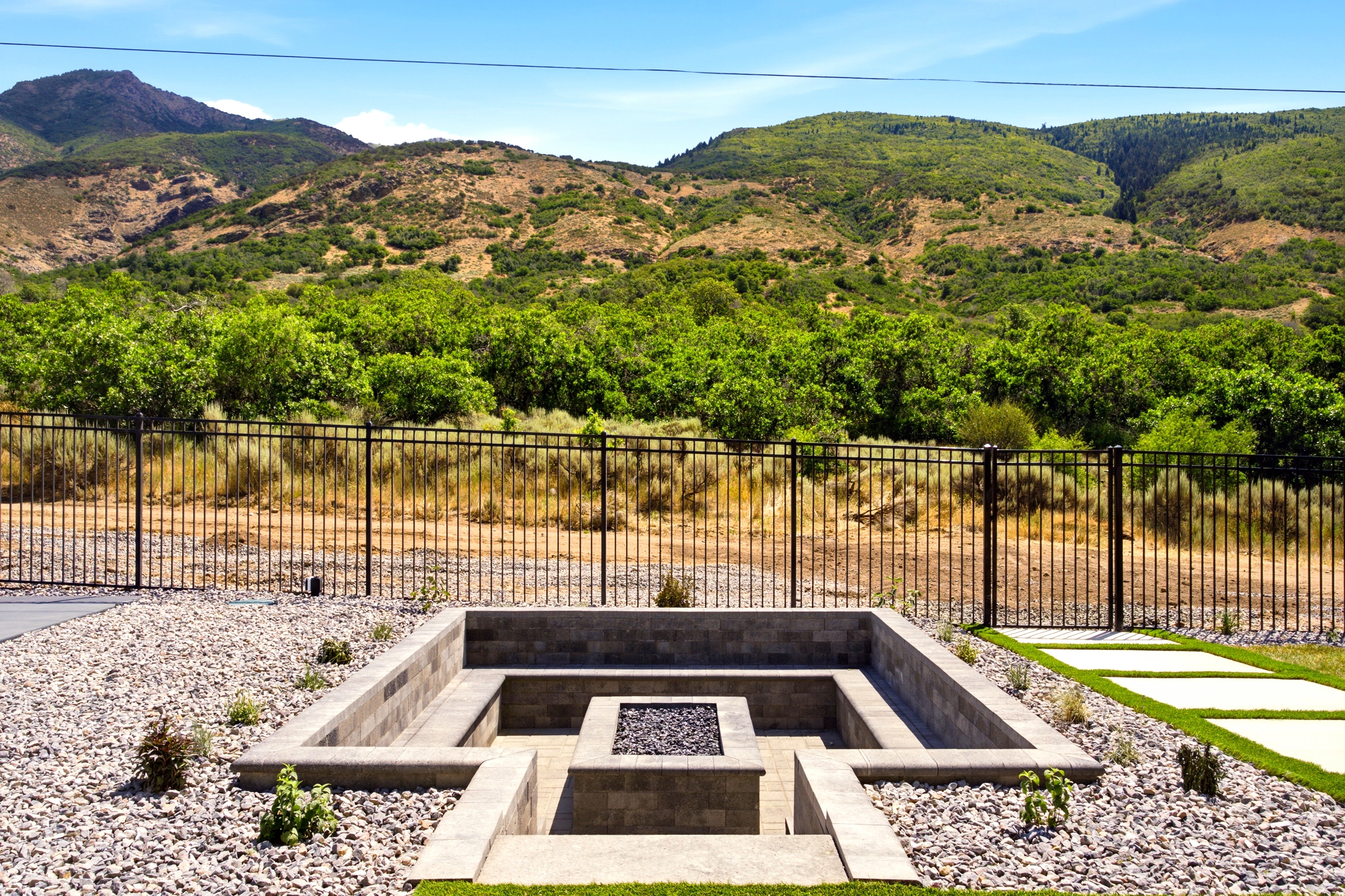Outdoor fire pit area featuring stacked stone surround, integrated seating, and decorative gravel
