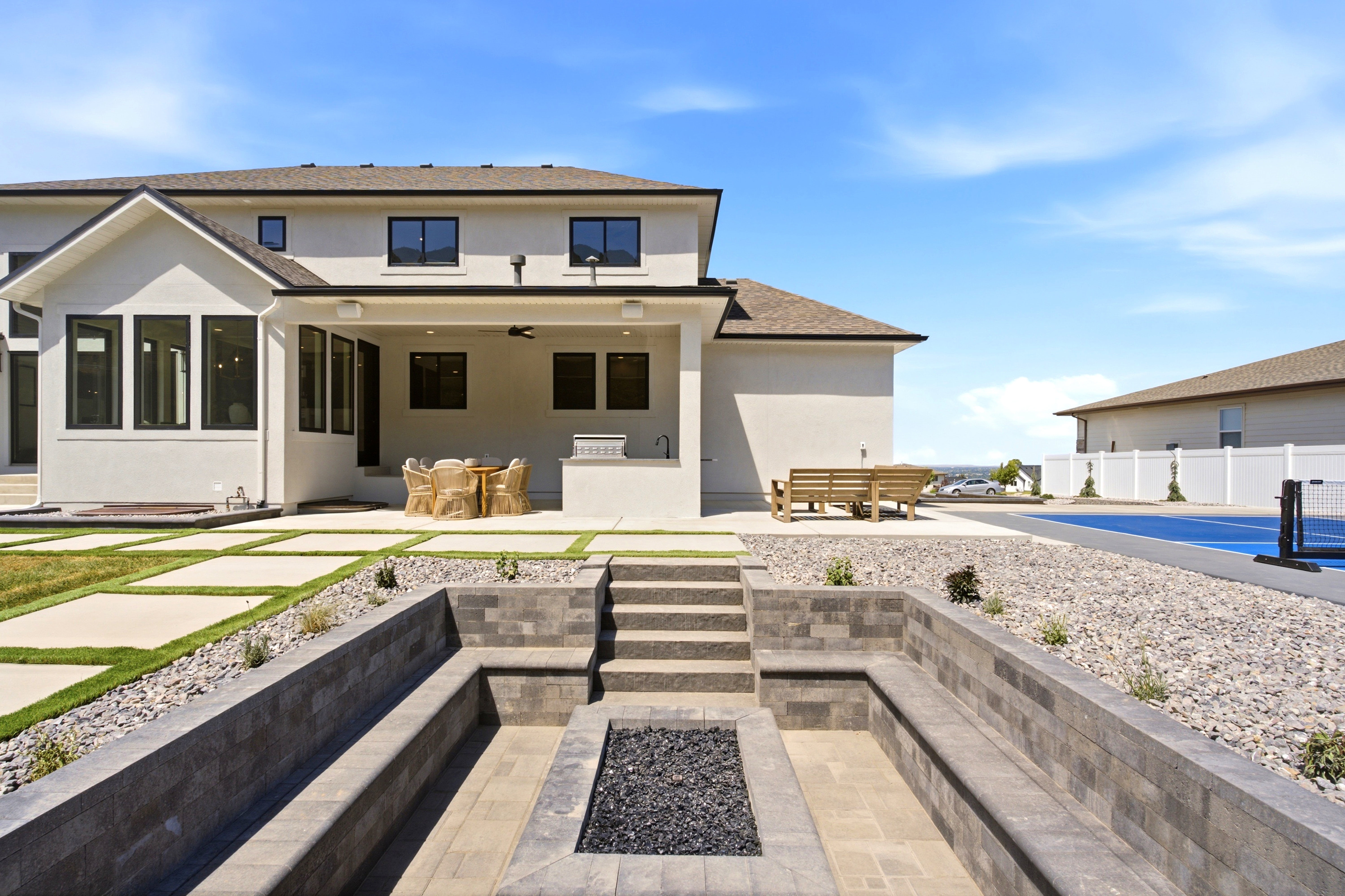 Sunken patio featuring a built-in fire pit with lava rock, integrated stone seating, and paver flooring