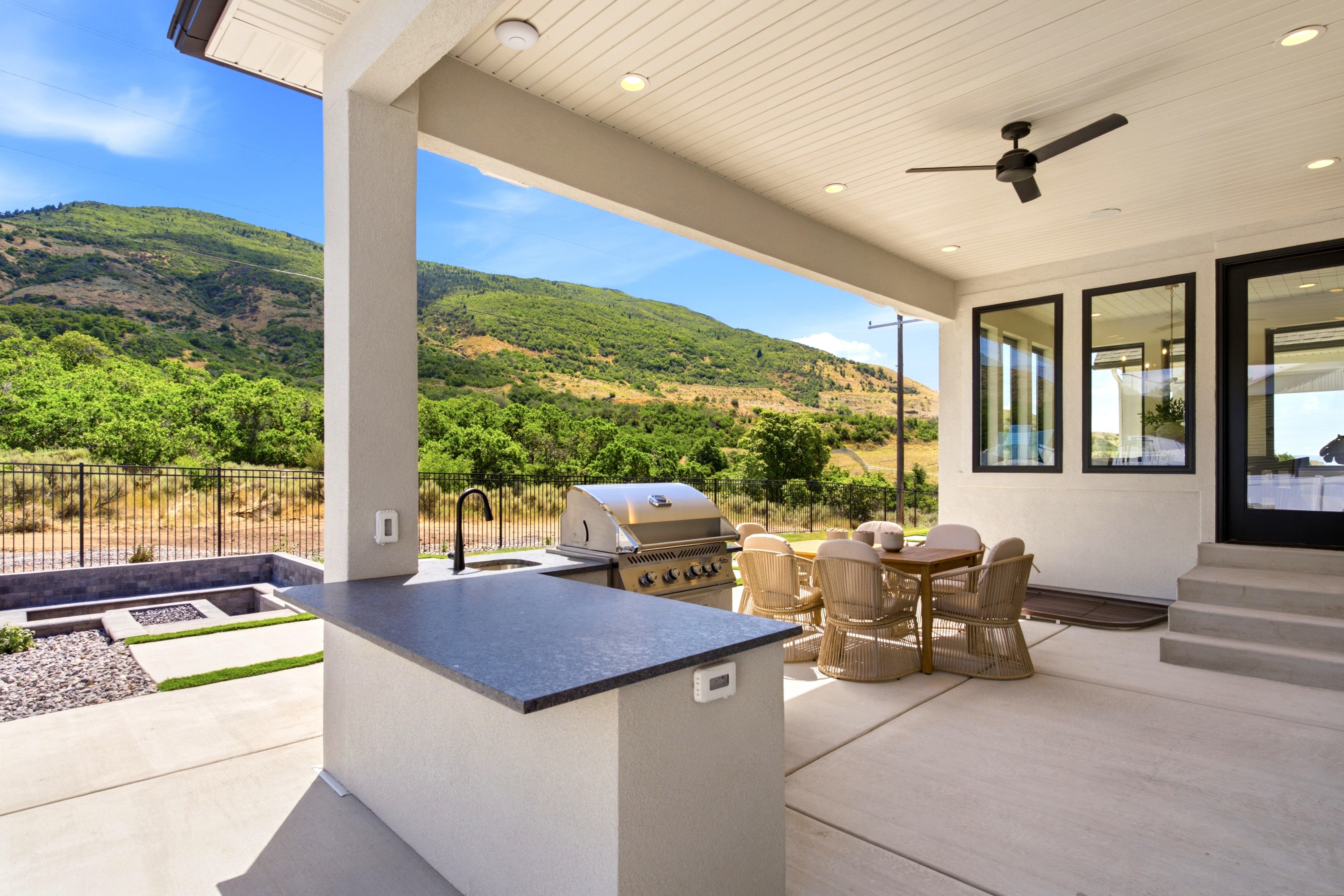 Covered patio featuring an outdoor kitchen with a built-in grill and sink, a ceiling fan, recessed lighting, and an integrated fire pit area