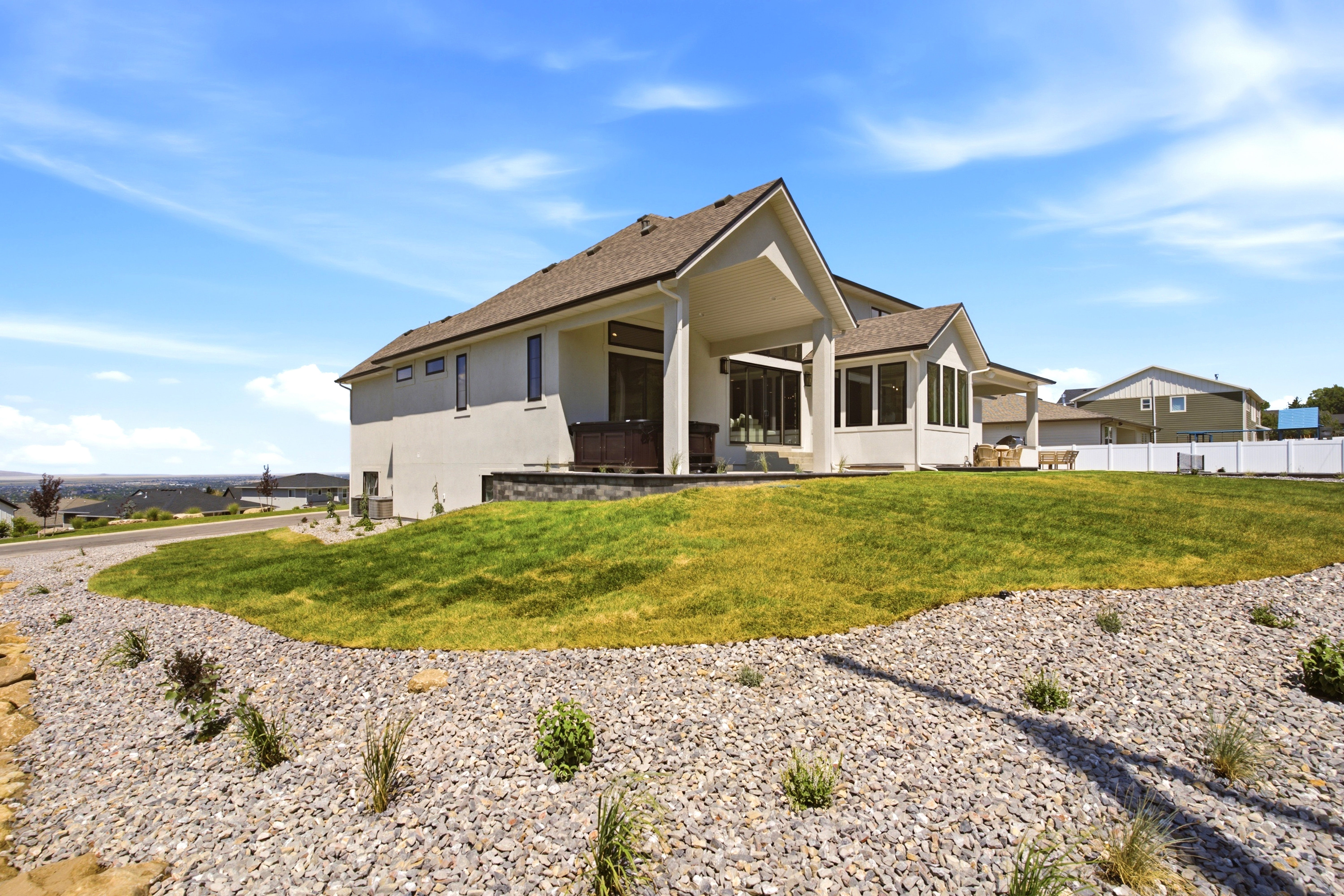 Contemporary stucco residence featuring a covered patio, extensive windows, and a sunroom