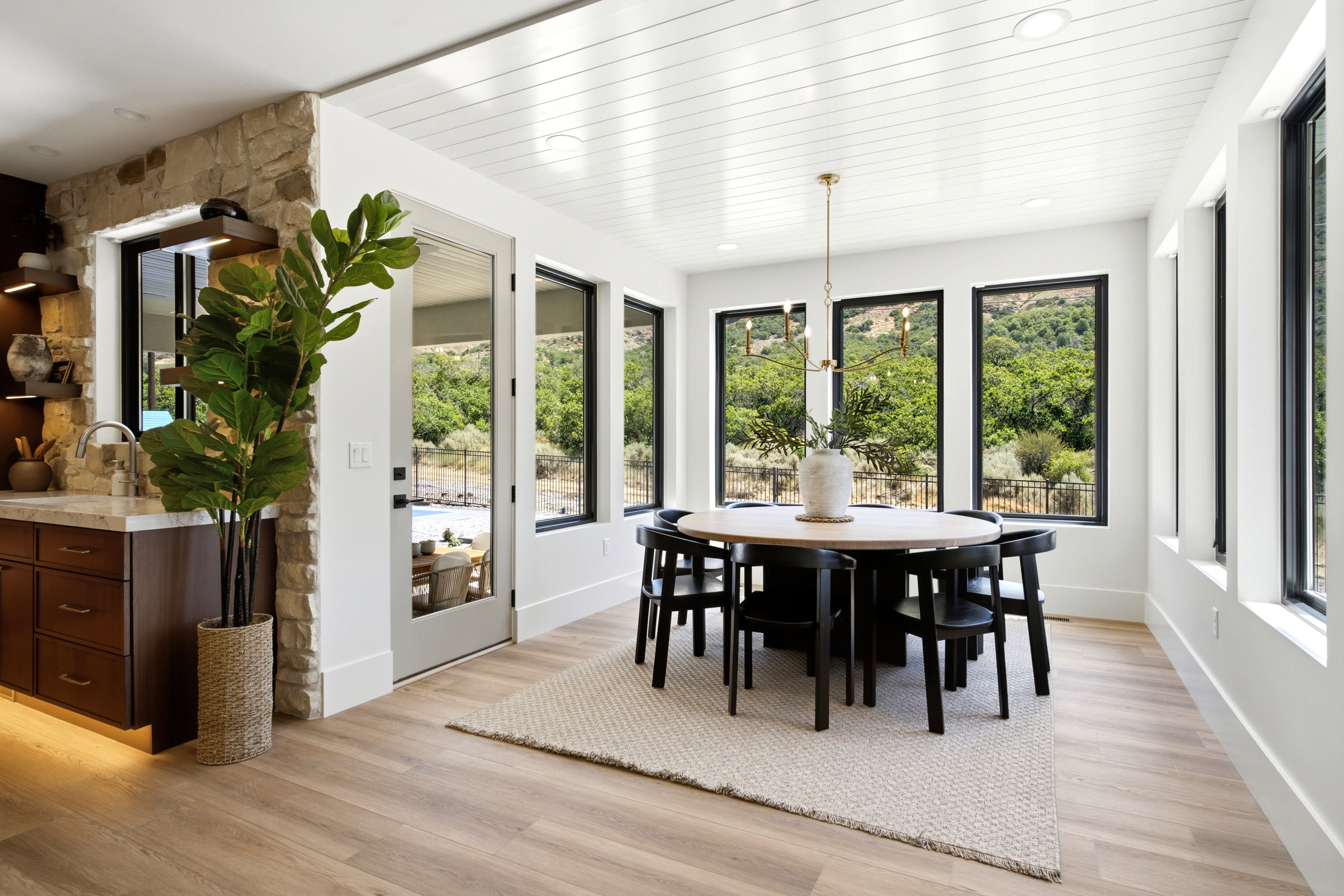 Dining area featuring a contemporary chandelier, multiple full-height windows, light wood-finish flooring, and white shiplap ceiling