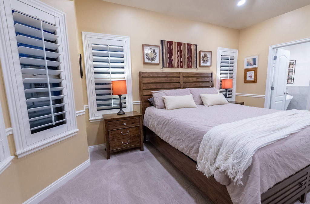 Bedroom featuring carpet flooring and multiple windows with white plantation shutters