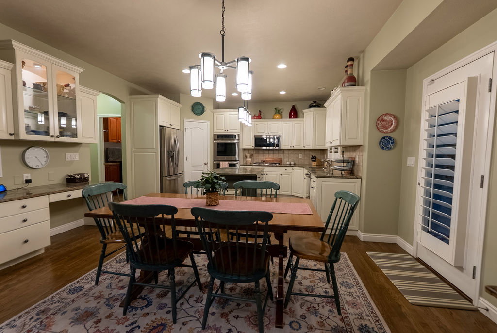 Spacious kitchen and dining area featuring cream-colored cabinetry, stainless steel appliances, a center island, and wood-finish flooring