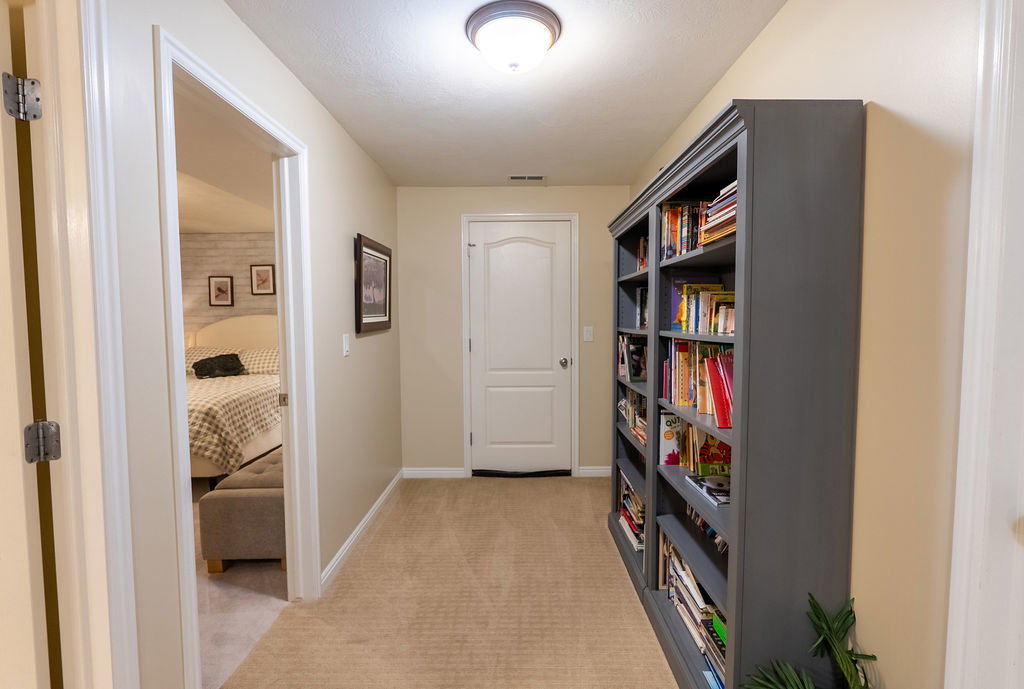 Hallway featuring neutral carpet flooring, recessed lighting, white trim, a built-in bookshelf, and a door with an arched panel design