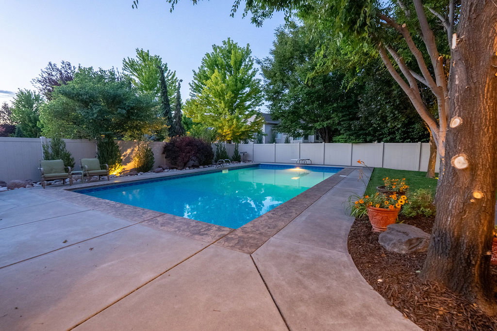 Rectangular in-ground swimming pool featuring a concrete surround and integrated lighting