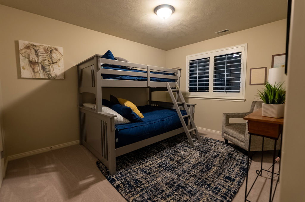 Carpeted interior room featuring light beige walls and a single window with white plantation shutters