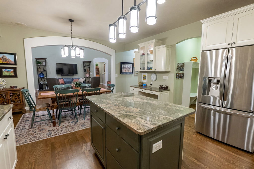 Kitchen featuring a center island with a stone countertop, wood-finish flooring, white upper cabinetry, and stainless steel appliances