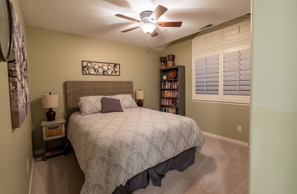 Ceiling fan with light fixture, plantation shutters, wall-to-wall carpeting, and sloped ceiling