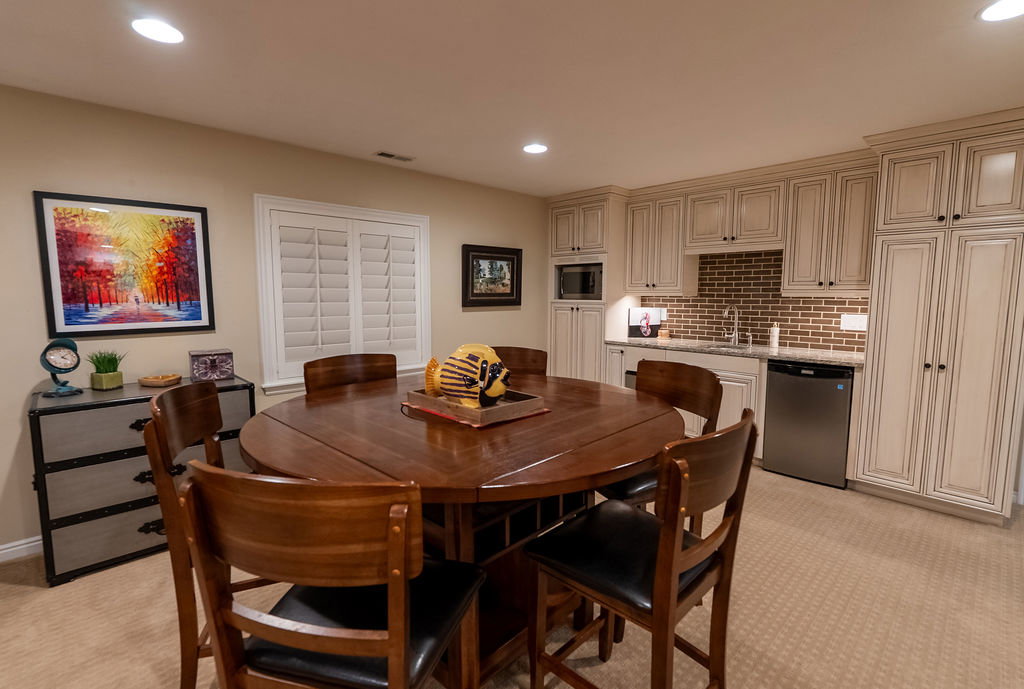 Built-in kitchenette featuring full-height cabinetry, brick-style backsplash, stainless steel sink, and integrated microwave