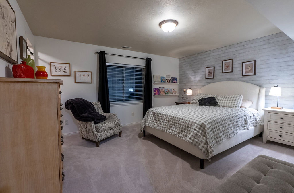 Bedroom featuring light gray carpeting and a white shiplap accent wall