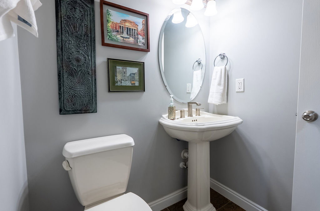 Pedestal sink with brushed nickel faucet and oval mirror