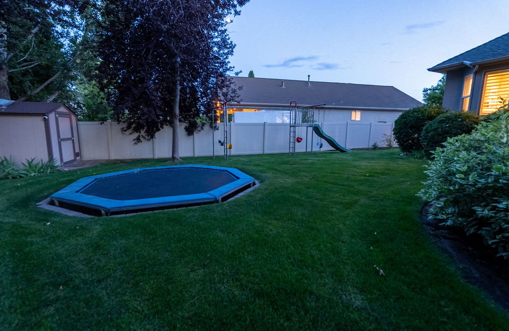 Expansive green lawn with mature landscaping and a perimeter privacy fence