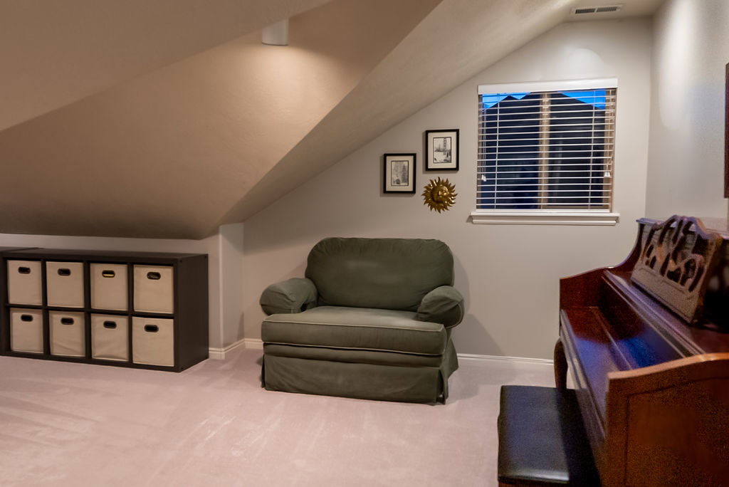 Sloped ceiling room featuring a window with blinds, recessed lighting, and light-toned carpeting