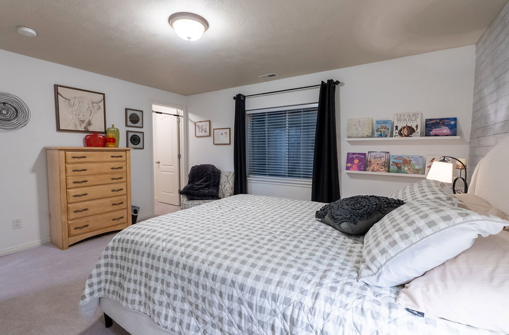 Bedroom featuring neutral wall paint, light-toned carpeting, and a window with blinds