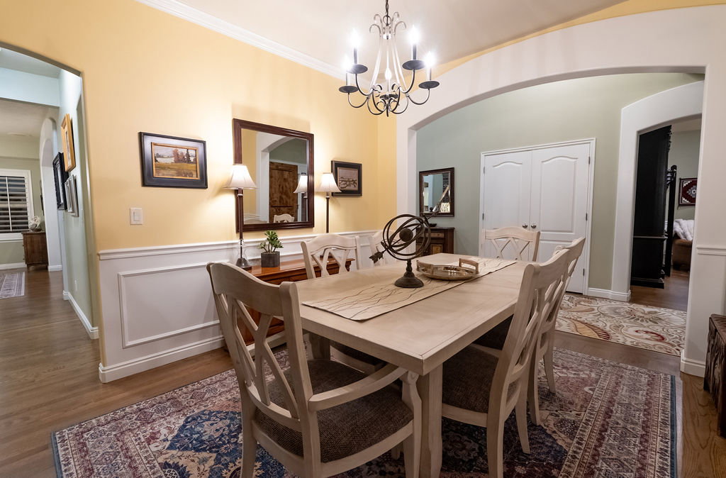 Dining area featuring wood-finish flooring, wainscoting, and crown molding