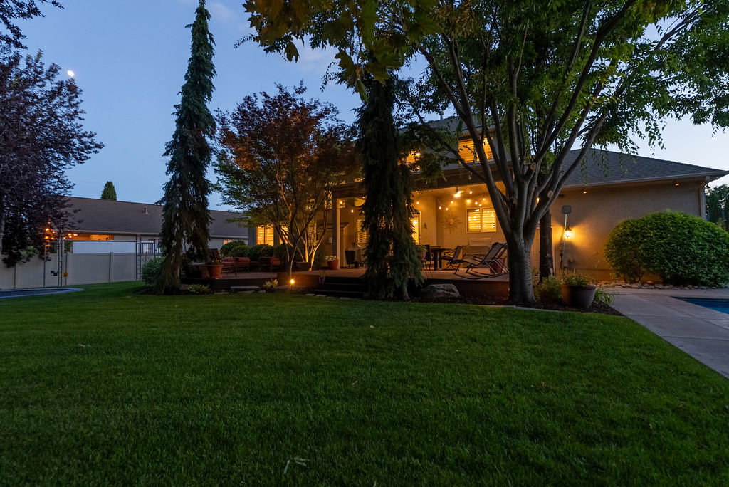 Expansive lawn area featuring mature trees and a concrete pathway