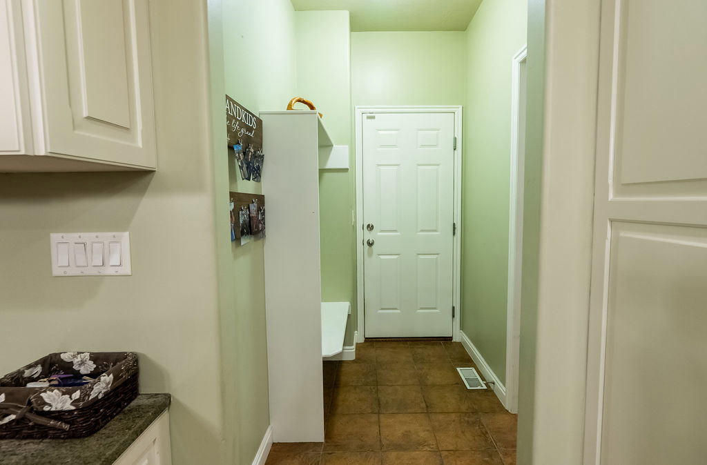 Entryway featuring a six-panel door, terracotta-toned tile flooring, and a built-in storage bench with shelving