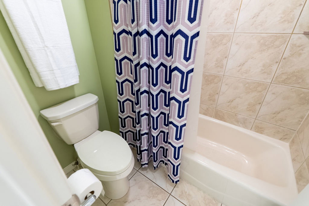 Bathroom featuring a full bathtub with light-toned tile surround, ceramic tile flooring, and a standard toilet