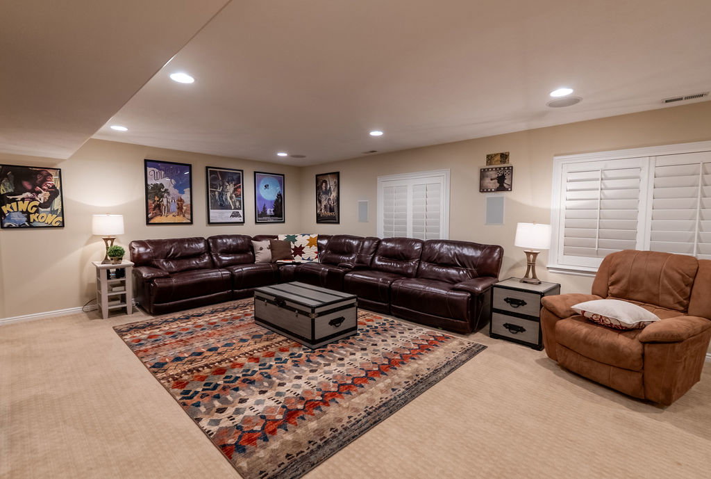 Recessed lighting illuminates this carpeted room featuring multiple windows with louvered shutters