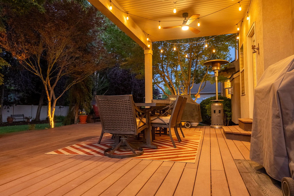 Covered outdoor deck featuring string lighting and a ceiling fan