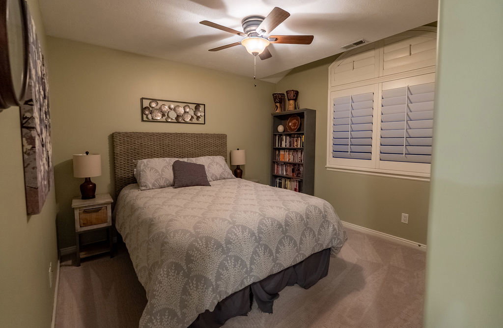 Interior room featuring a ceiling fan with integrated lighting, a window with white plantation shutters, and light-colored carpeting