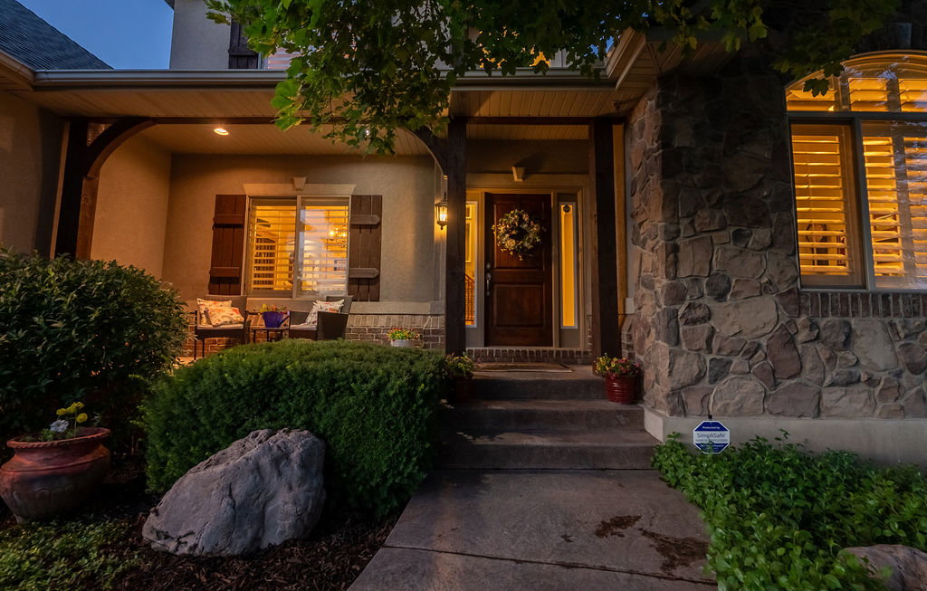 Stone facade and stucco exterior featuring a covered front porch with exposed wood beams, a paneled entry door, and a concrete walkway