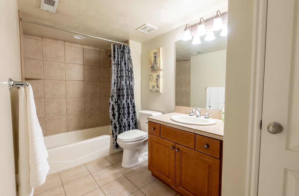 Bathroom featuring a tiled shower surround, white bathtub, tile flooring, and a vanity with a counter-mounted sink