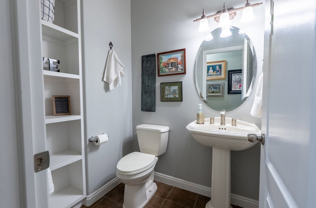Pedestal sink with brushed nickel faucet, wall-mounted mirror, and vanity lighting