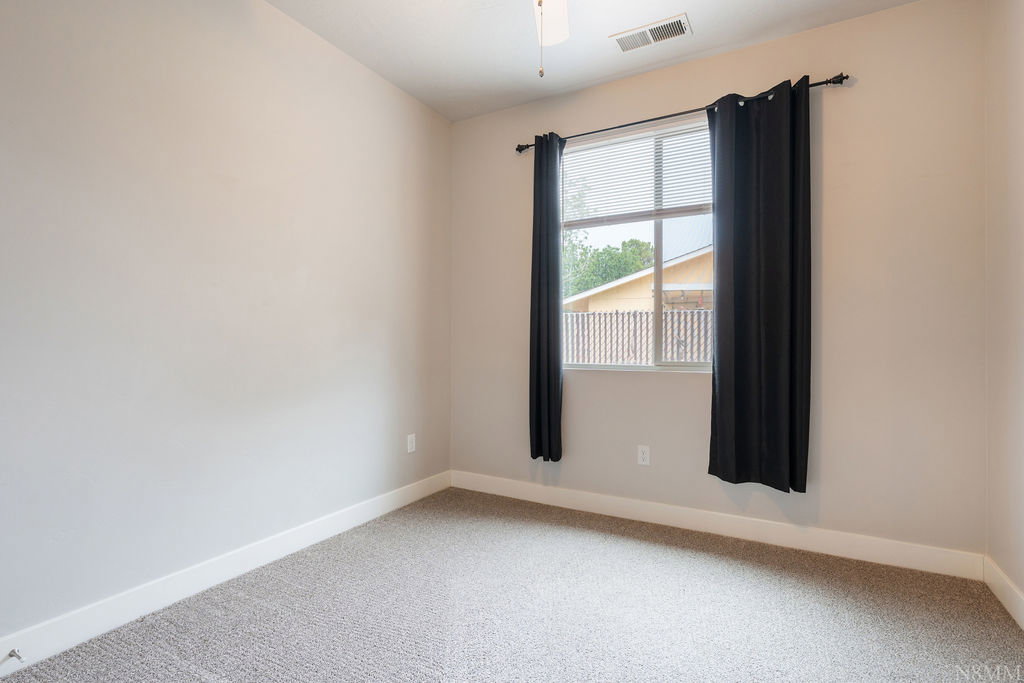 Neutral wall color, window with blinds, dark curtains, ceiling fan, and carpeted flooring