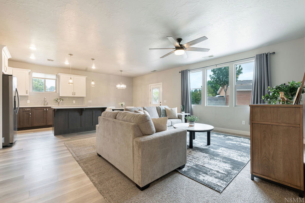 Open-concept living space featuring a contemporary kitchen, light wood-finish flooring, and ample natural illumination through multiple windows