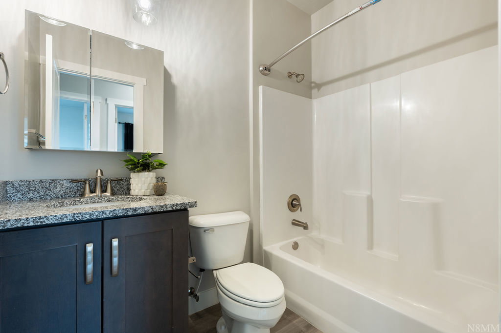 Bathroom featuring a dark wood-finish vanity with a granite-style countertop and undermount sink
